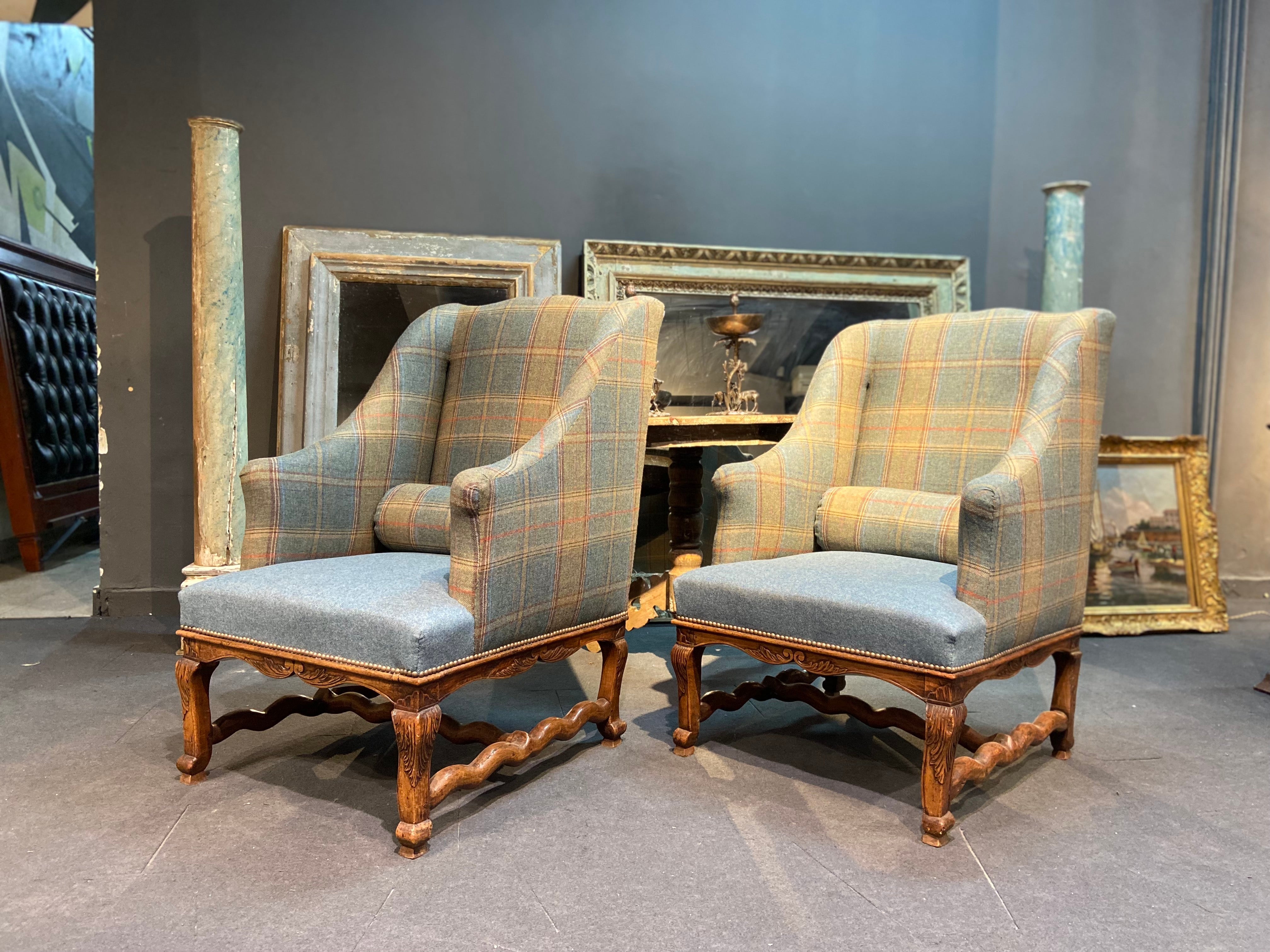 Two French armchairs forming a pair, but could be used separately as an accent in your home. Frames are carved wooden sheep bones decorated with foliage scrolls with high winged backrest. The armchairs are newly upholstered in plain and gray blue
