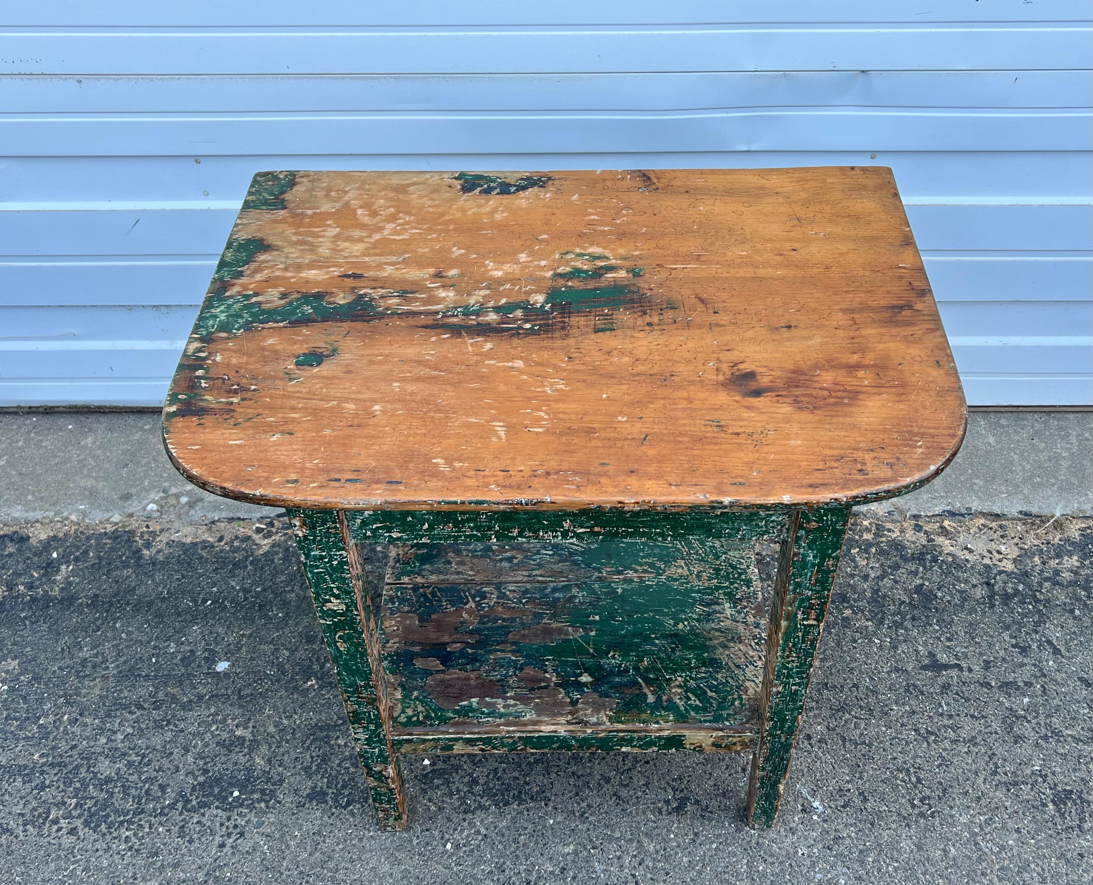19th century two tier side table crafted from pine with original rustic green paint.  Single board top with rounded front corners.  From New Brunswick.