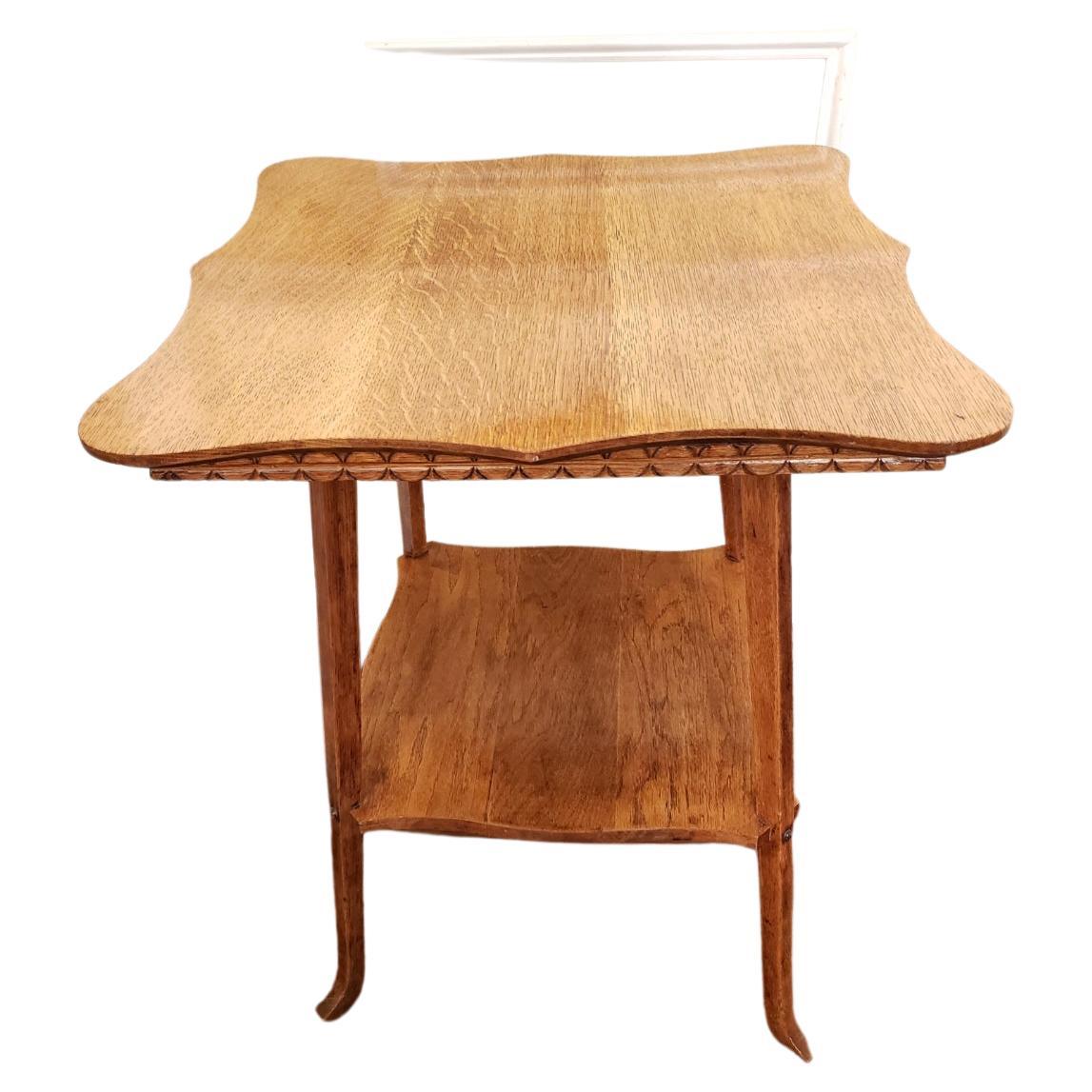 Cette table à deux niveaux de la fin du 19e siècle comprend un grand plateau de table de 23::5 pouces carrés avec des bords sculptés:: ainsi qu'un second plateau inférieur avec... Elle est fabriquée en bois de chêne massif à 100 % et convient à