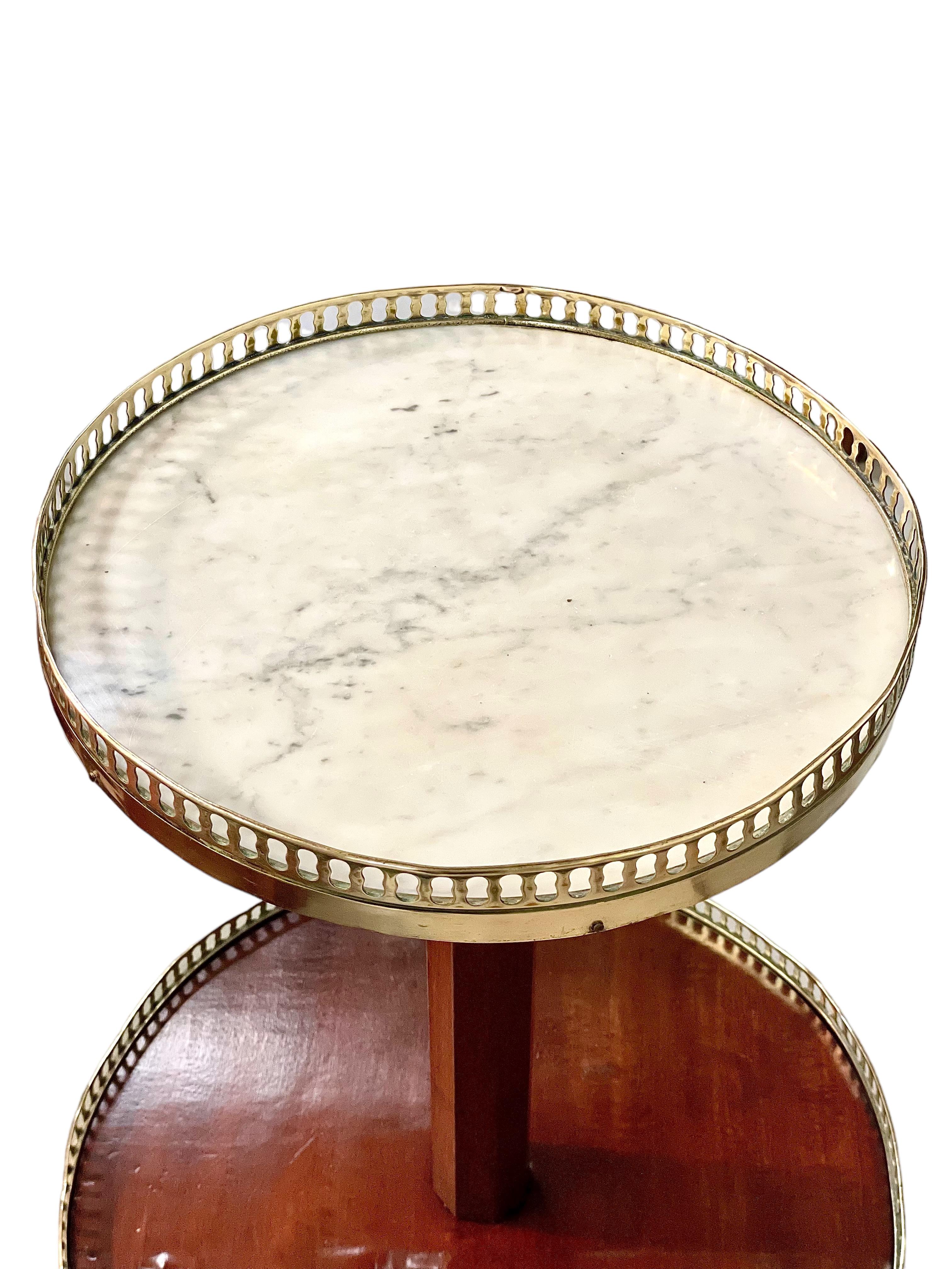 This superb antique two-tiered 'Dumb Waiter' serving table dates from the end of 19th century, and is beautifully constructed in mahogany veneer and marble. Crafted in the Louis XVI style, it features two graduated mahogany shelves, each enclosed by