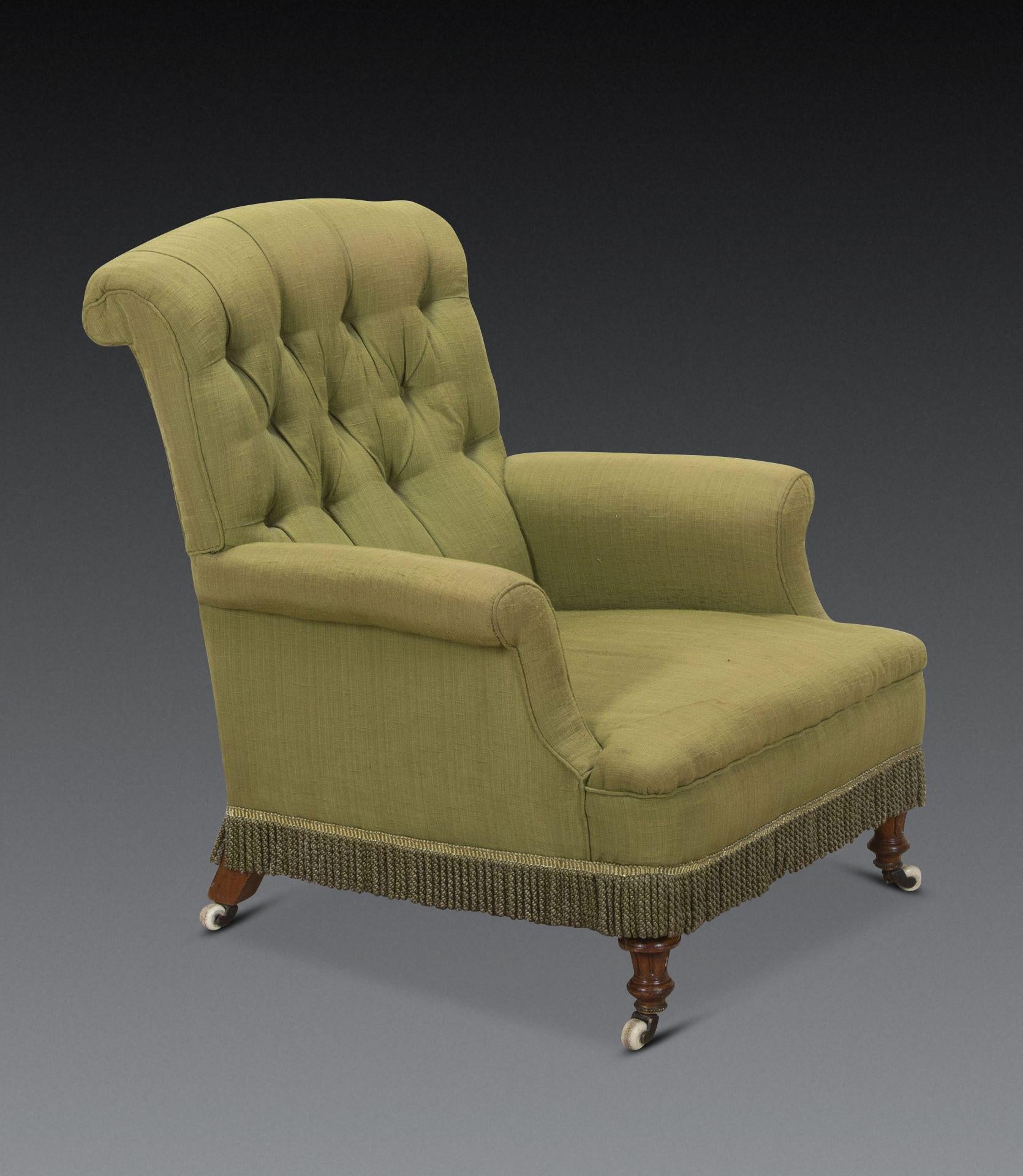 Una comoda poltrona inglese del XIX secolo.
Rivestito in modo ordinato in tessuto di lino spazzolato verde salvia, con schienale abbottonato. Si erge su gambe in noce tornite e scanalate con rotelle originali, dietro a nappe intrecciate. 
Circa