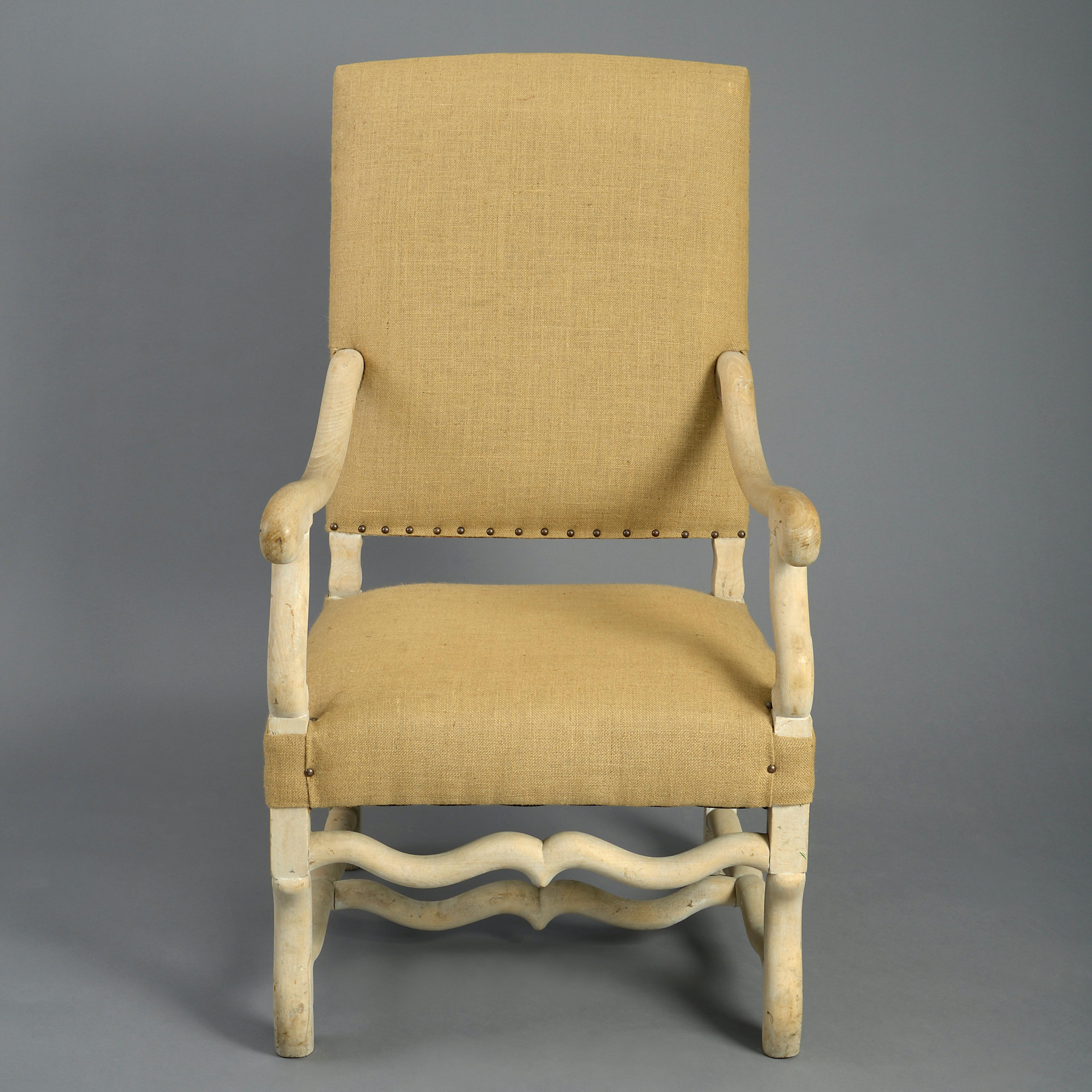 A late 19th century beechwood open armchair in the seventeenth century French Baroque manner, the upholstered back and seat with scrolling arms, all supported on scrolling legs with shaped stretchers.
