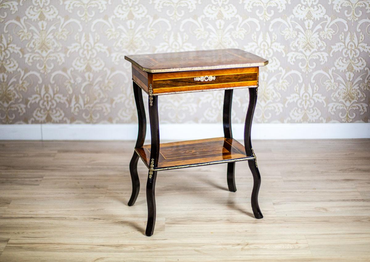 We present you an antique piece of furniture, circa 1880, which can be used as a vanity, a sewing table, a whatnot, or as a nightstand.
It is composed of a small chest with a liftable desktop.
All is supported on slightly bent legs with a shelf at