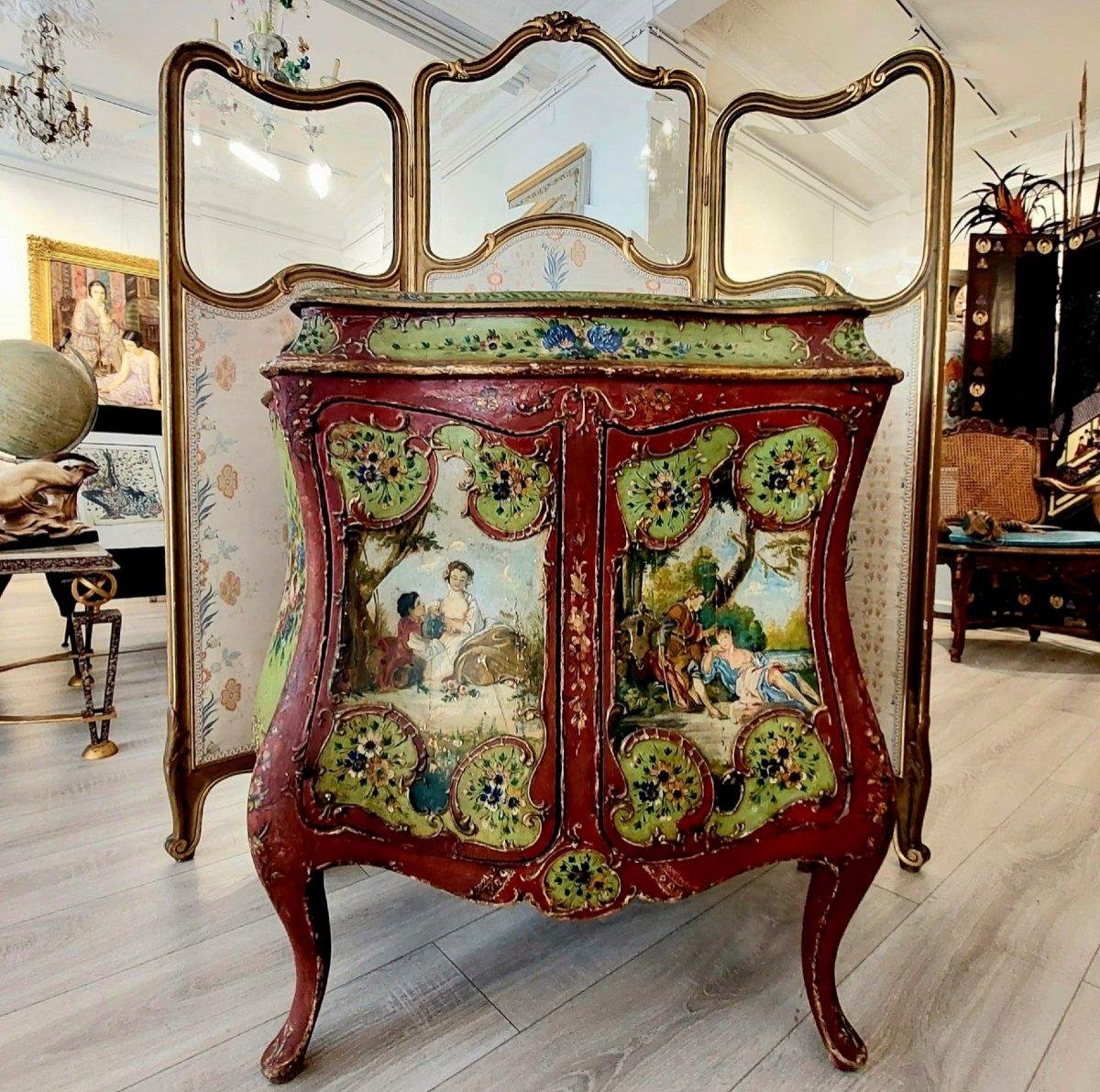 Crafted from lime green and red lacquered wood, this exquisite bombe-shaped bahut sideboard is meticulously hand-carved with amorous scenes and intricate floral patterns. Crowning the sideboard is a glass-topped display cabinet, designed to