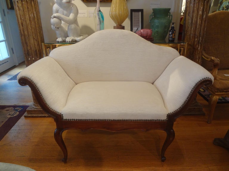 Chic 19th century Venetian walnut loveseat, canape or divanetto with a beautiful shapely back, scrolled arms and cabriole legs. This charming loveseat has been professionally upholstered in high quality cream colored striated cut velvet fabric.