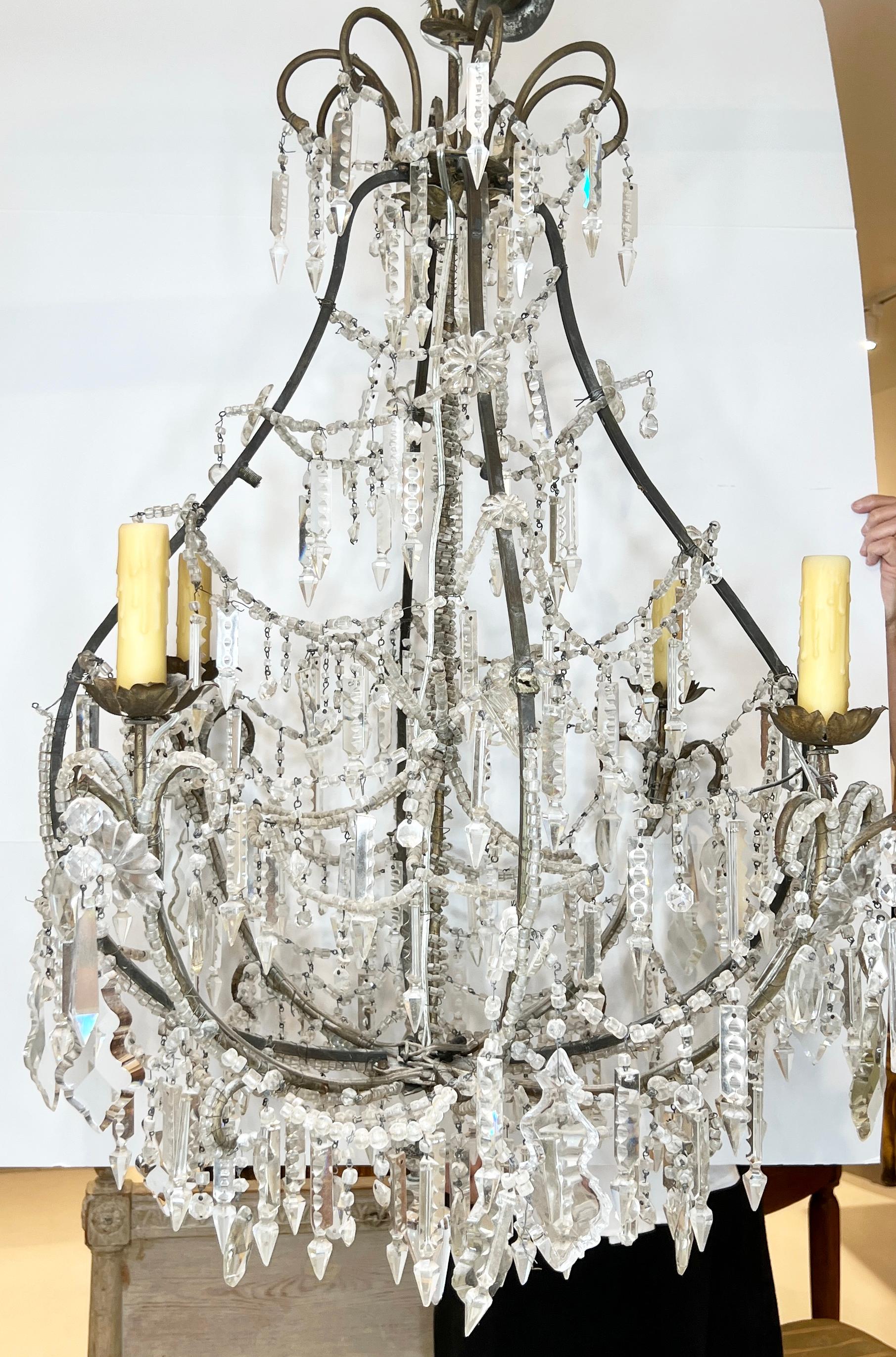 19th century Venetian chandelier graces any space with its classic crystals draped around the iron frame and lower portion. Crystal beads and drops adorn this unique iron contour to glamorize any space.  Wired for US, but not UL approved.