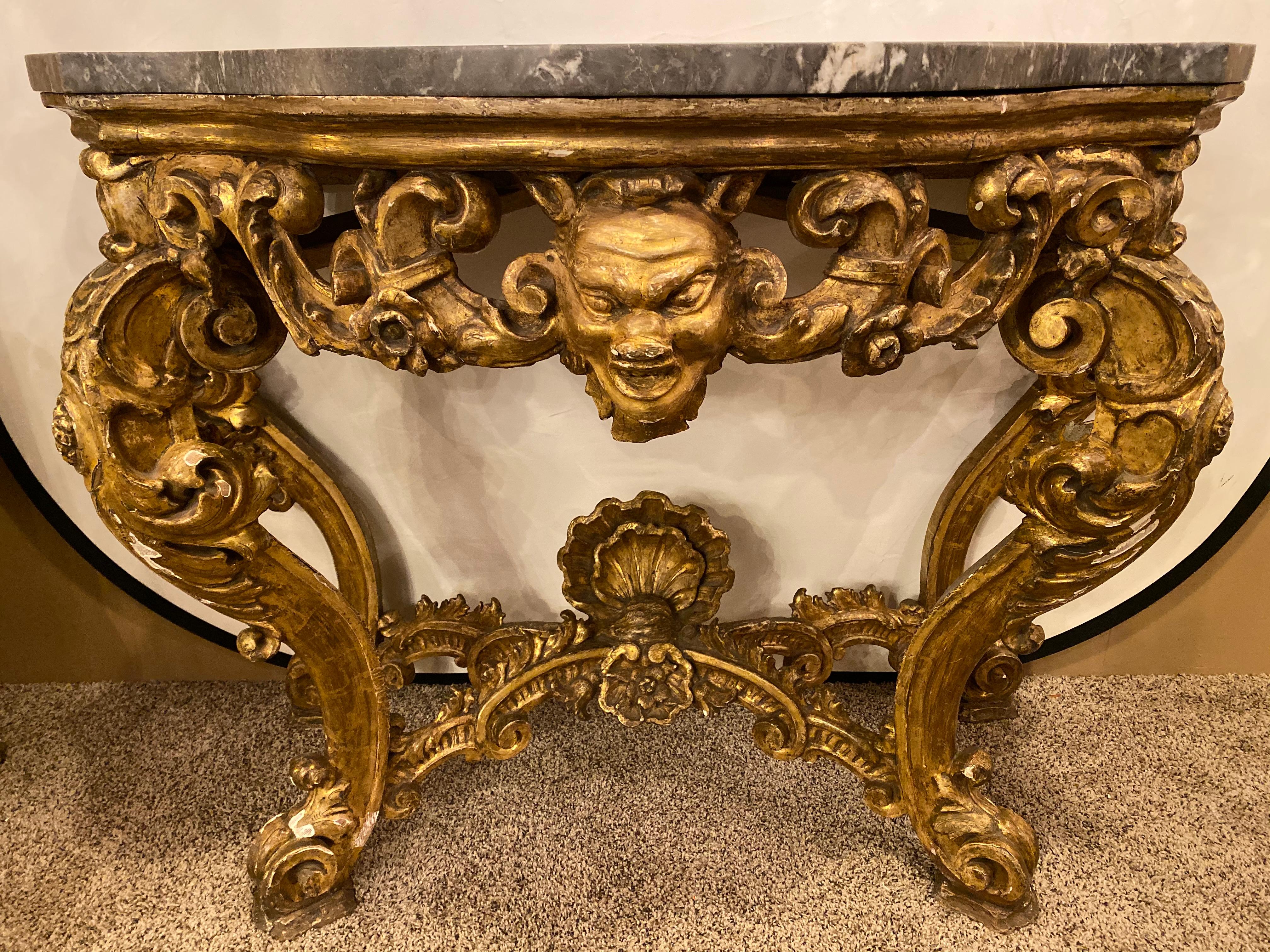 19th century Venetian gilt gold console table having a grey marble top. This ornately carved console or serving table is simply stunning and was certainly crafted to make a statement in any room it sits in. The double serpentine form case with a