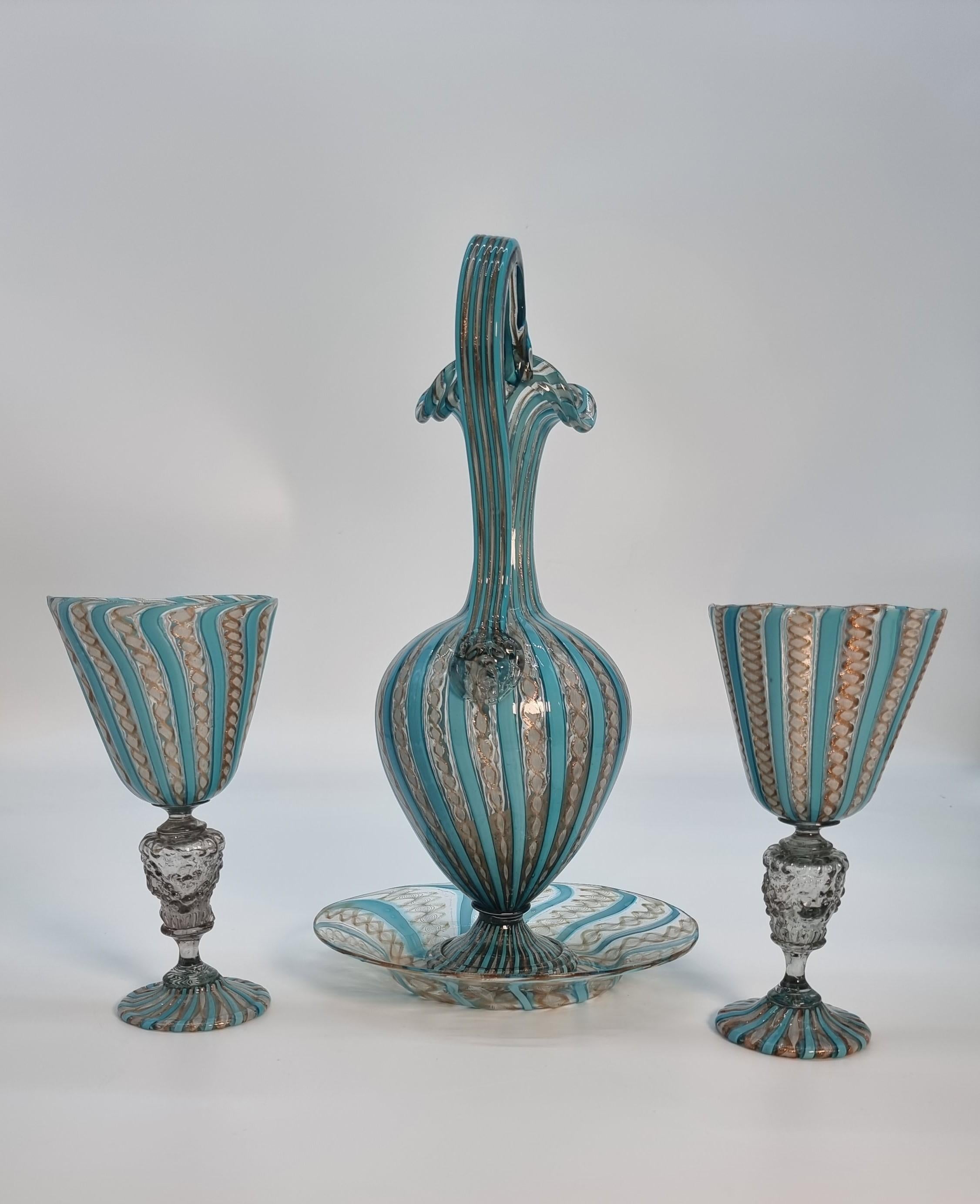 A superb Venetian lattico glass claret jug/ewer complete with matching stand and a pair of goblets

This beautiful set of Venetian lattice. glass is amazing. It has a jewel like quality which is very pleasing to the eye. It has an intricate and fine