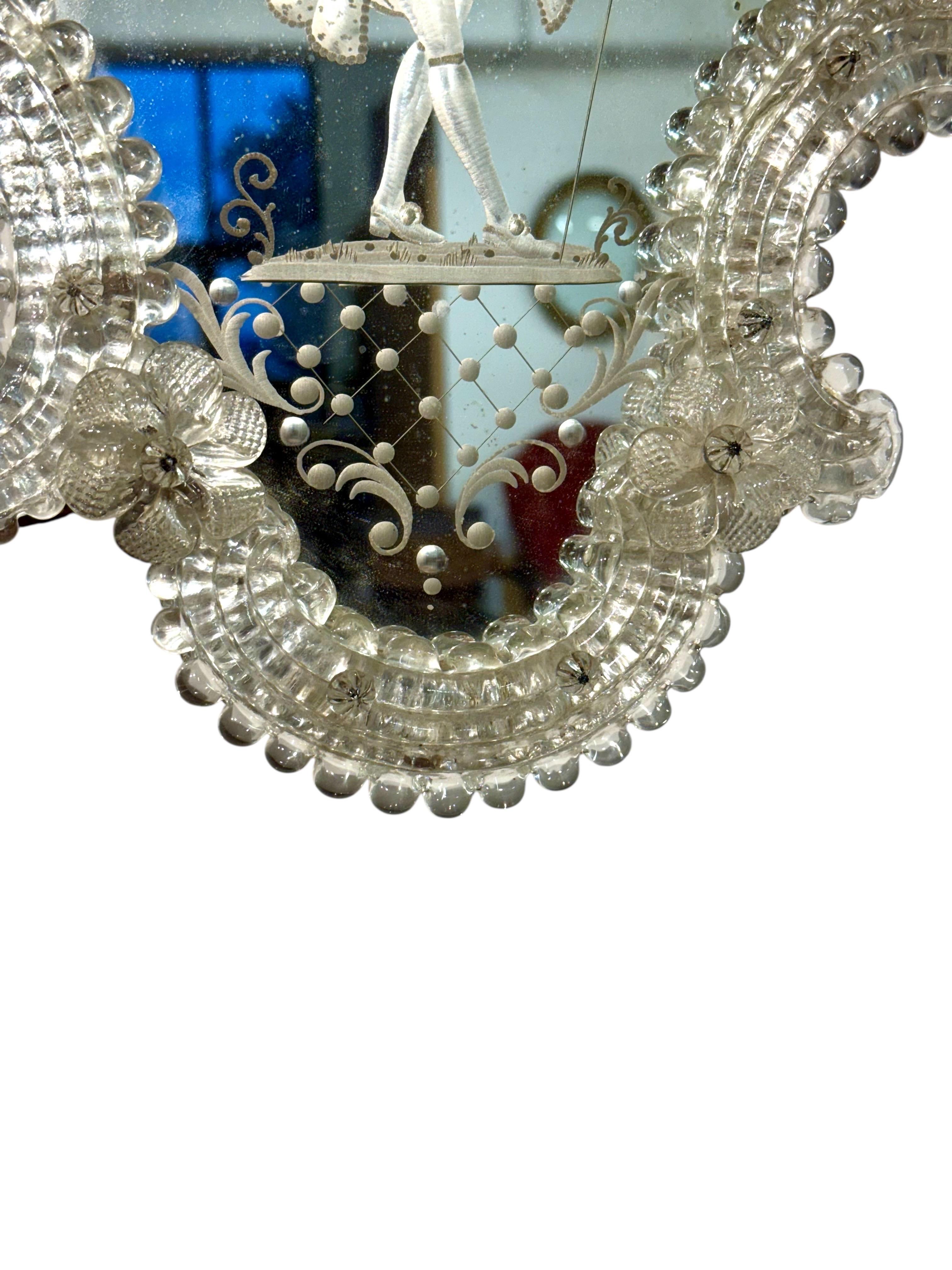 Cet authentique miroir vénitien est une magnifique pièce décorative du XIXe siècle, richement ornée d'éléments en verre soufflé à la main et de détails gravés raffinés. Son contour façonné est encadré par les tiges de verre festonnées