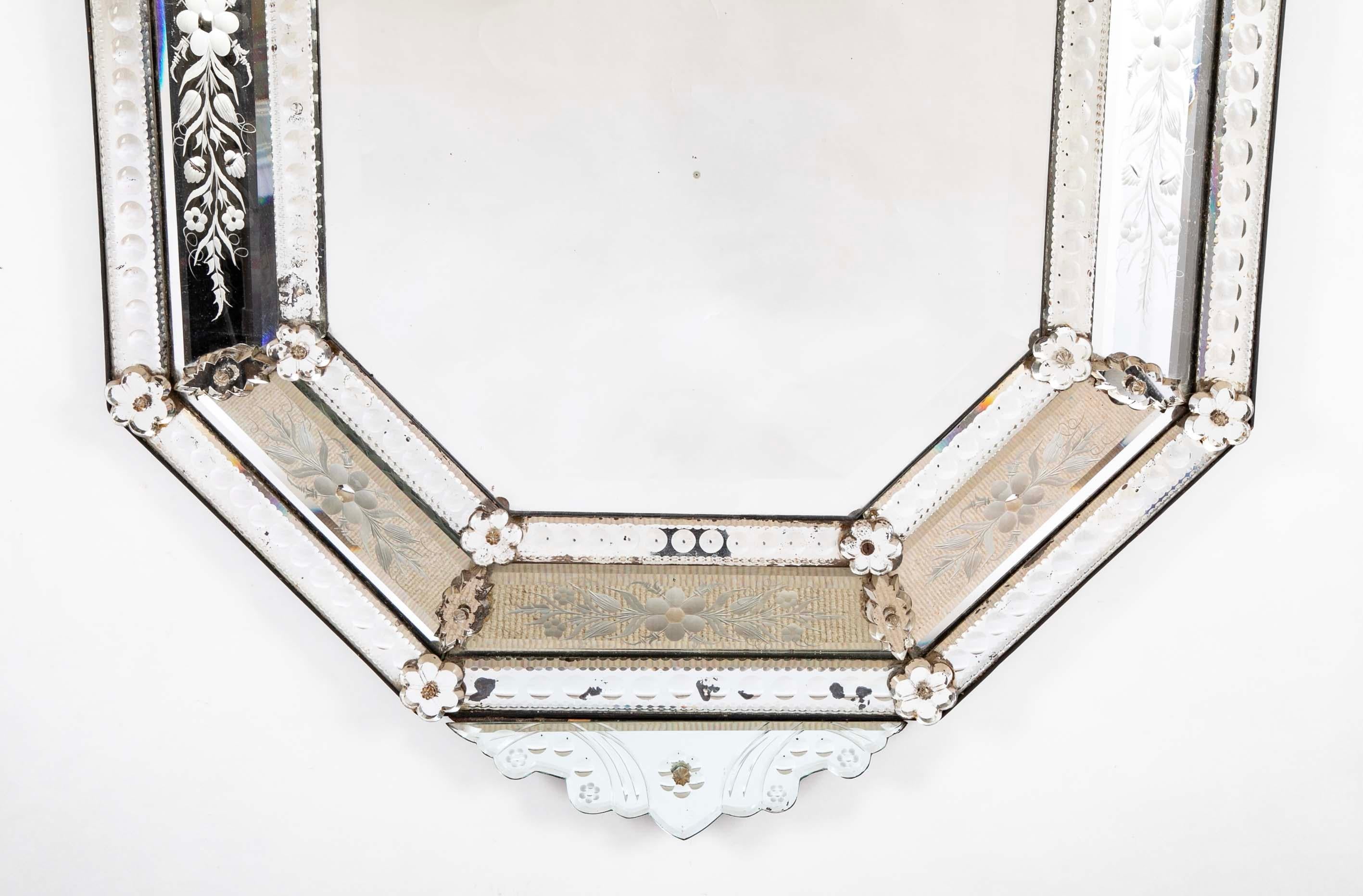 Espejo veneciano de cristal tallado del siglo XIX con decoración floral grabada. Las molduras exteriores e interiores con cenefas de piecrust y minicírculos convexos unidos por florones individuales y rombos geométricos. Rematado por una elaborada