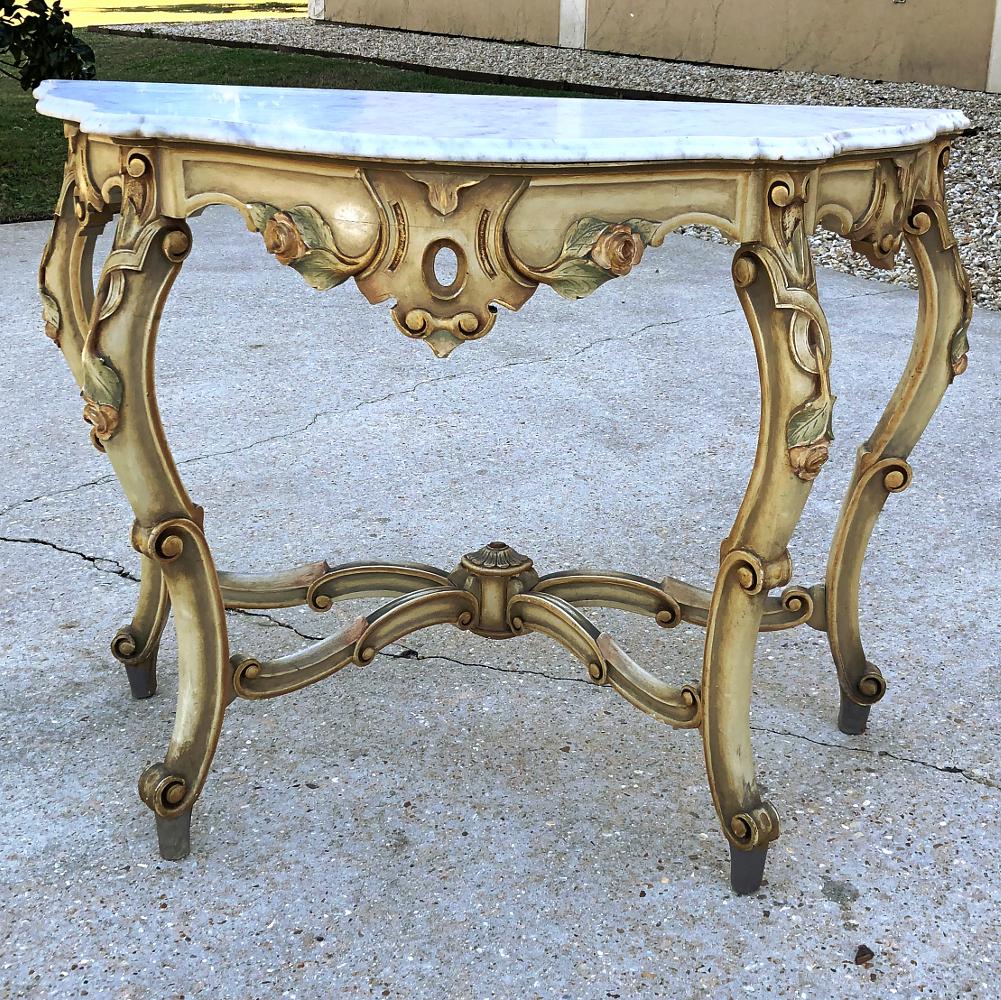 19th century Venetian painted marble top console features a bold heraldic crest centered on the elaborately contoured apron, flanked by cascading floral and foliate sprays accented with blushes of color appearing on each of the four legs. The