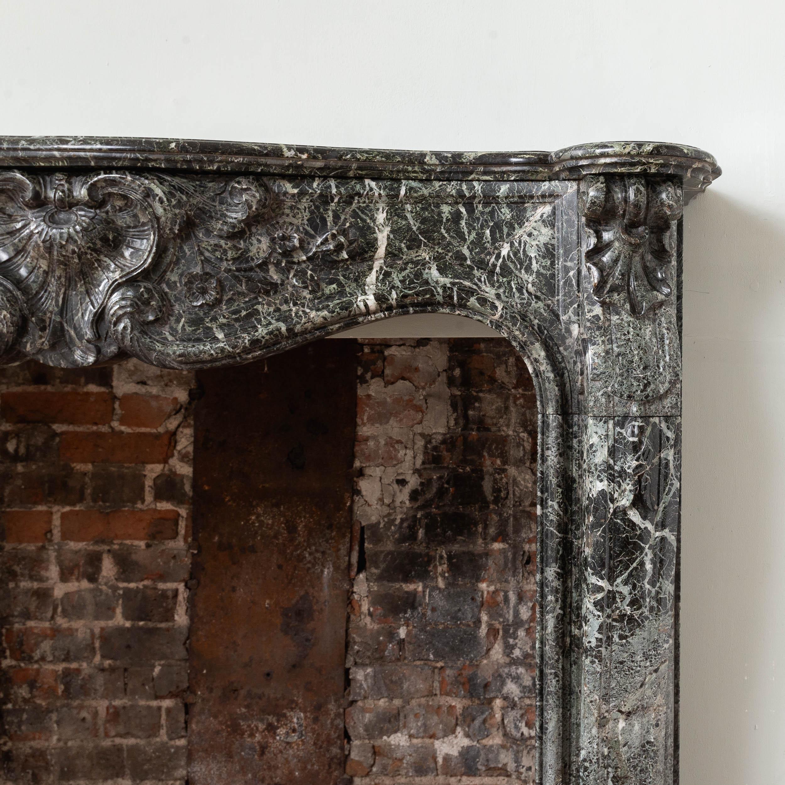 A Nineteenth century Verde Tinos fireplace, French or Italian, the frieze centred with cartouche and trails of flowers carved in relief, raised on scrolled jambs.

Dimensions:
120cm (47¼