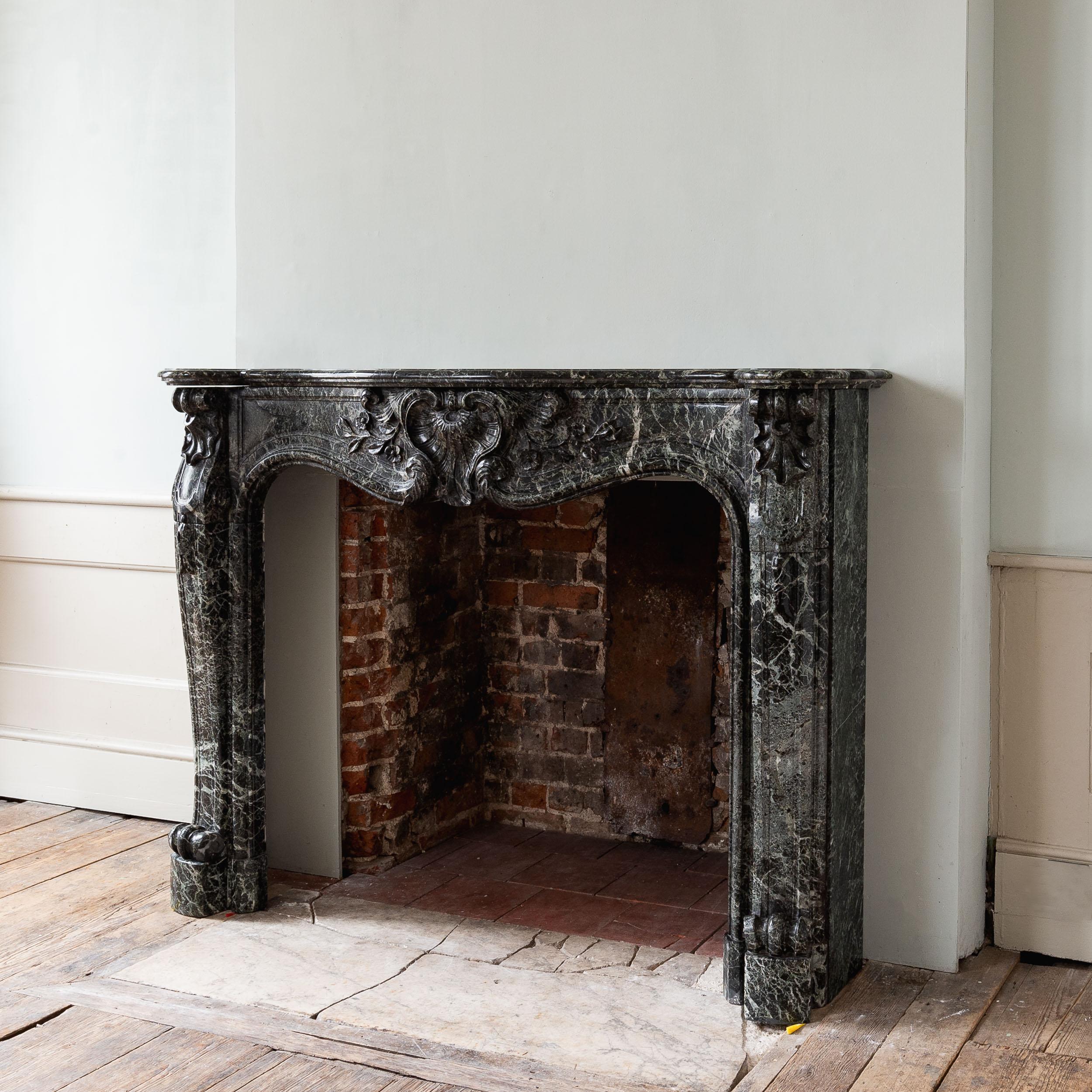 A Nineteenth century Verde Tinos fireplace, French or Italian, the frieze centred with cartouche and trails of flowers carved in relief, raised on scrolled jambs.

Restored, polished and ready to install.

Dimensions:	120cm (47¼
