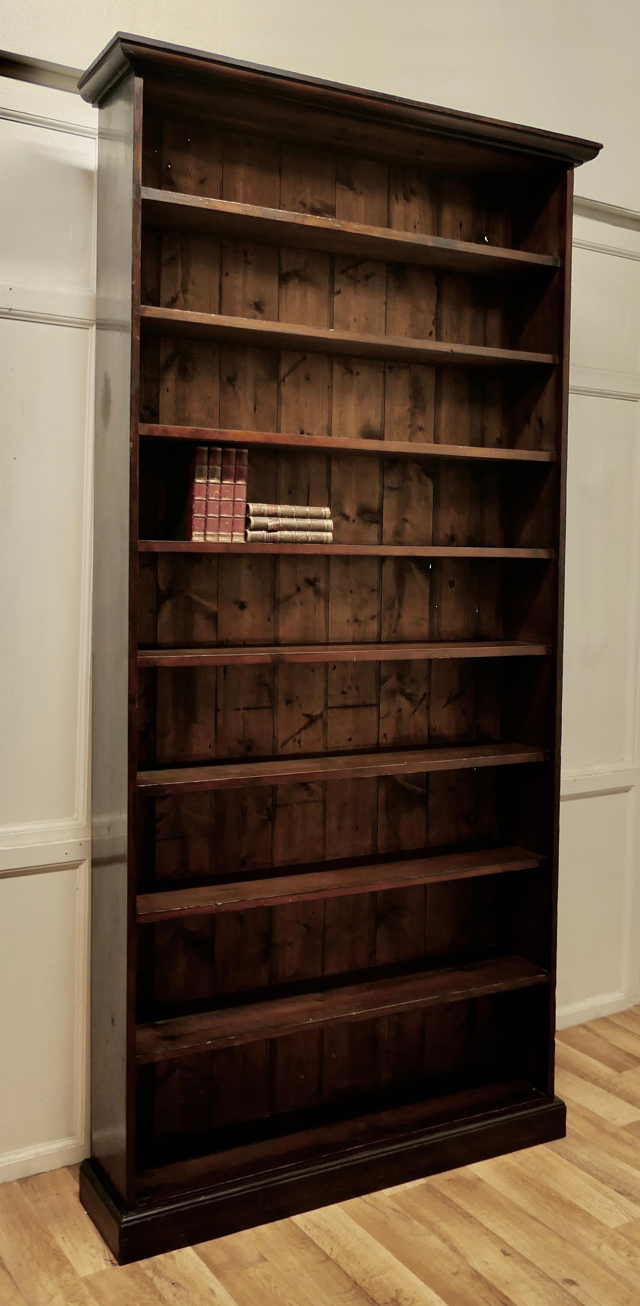 19th century very tall open book case, in dark pine

This is a classic timeless piece, the book case is hand made in thick pine, with a planked back, it has 9 open shelves, it has a small plinth and a neat cornice
All in all very good