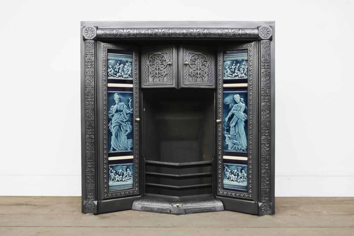 Rare antique aesthetic 'Gold Medal Eagle Grate'. Circa 1887. This very unusual tiled grate has two large doors each side to fitted with a set of antique fireplace tiles. Behind each of these tiled doors is a further three doors, the top door remains