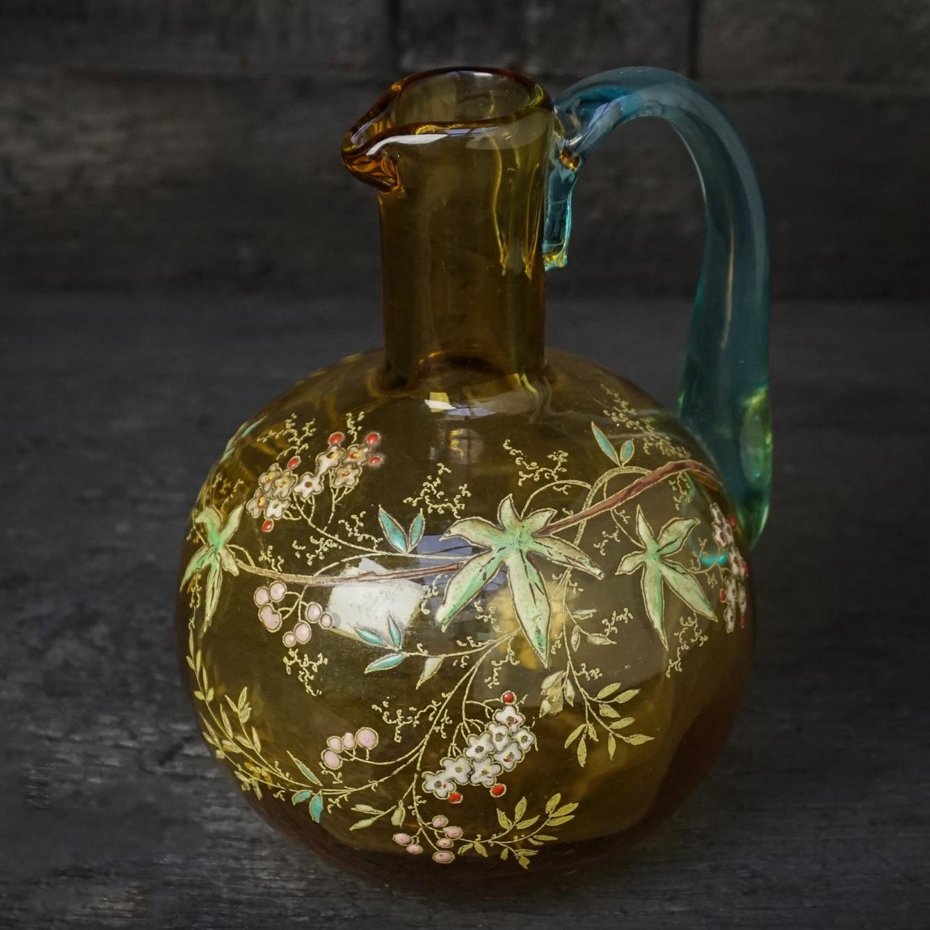 Sweet little handblown carafe or decanter in amber glass with a very detailed enamel decor of flower, berries and leaves. It has a blue handle.

Visible pontil, Legras' initial and number '44' on the bottom.
(A pontil is the scar where the