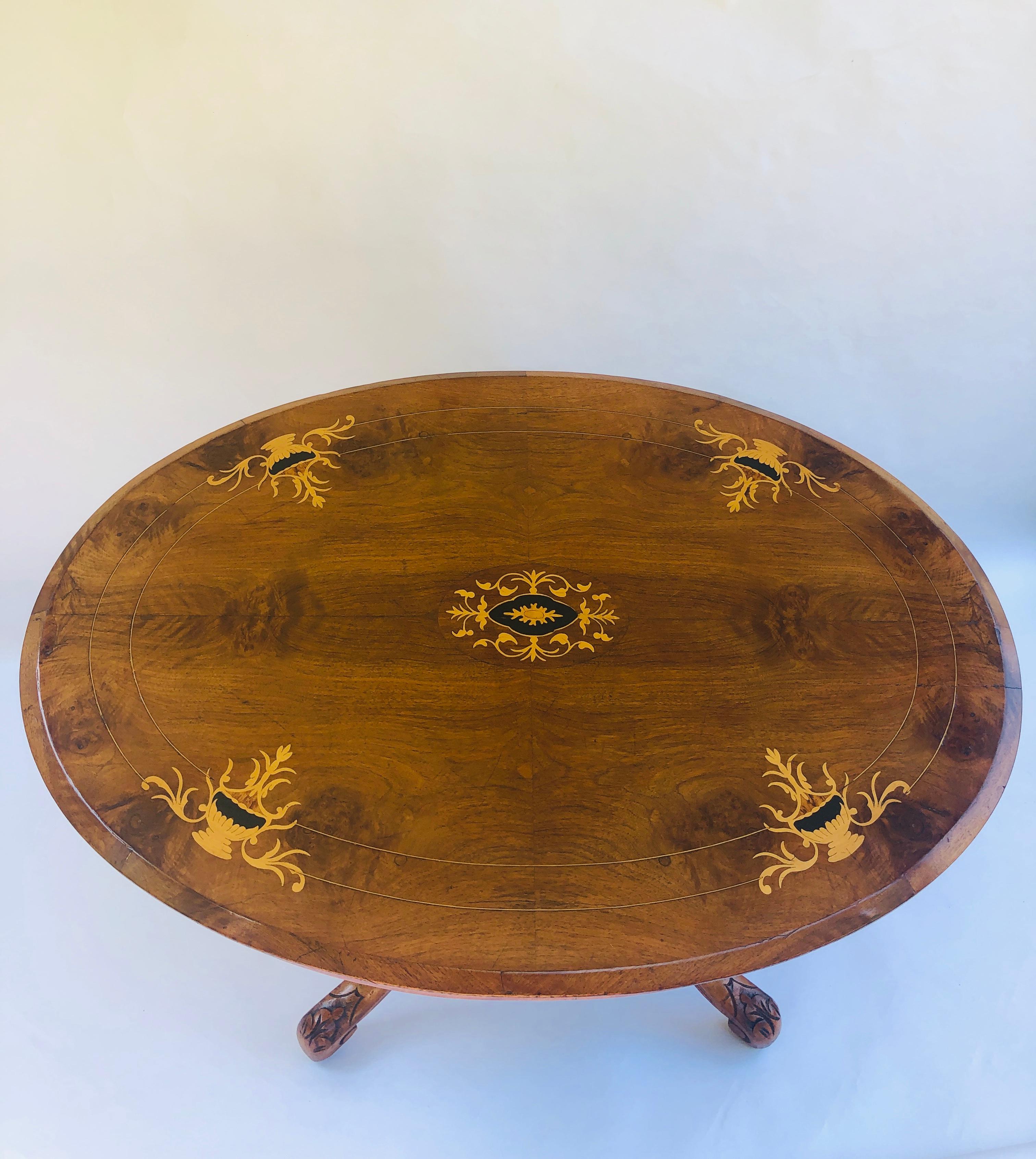 Antique Victorian walnut inlaid oval centre table having a charming walnut top with attractive boxwood inlay. The oval shaped frieze has boxwood stringing and the base has 4 splendid turned columns supported by 4 shaped carved cabriole legs standing