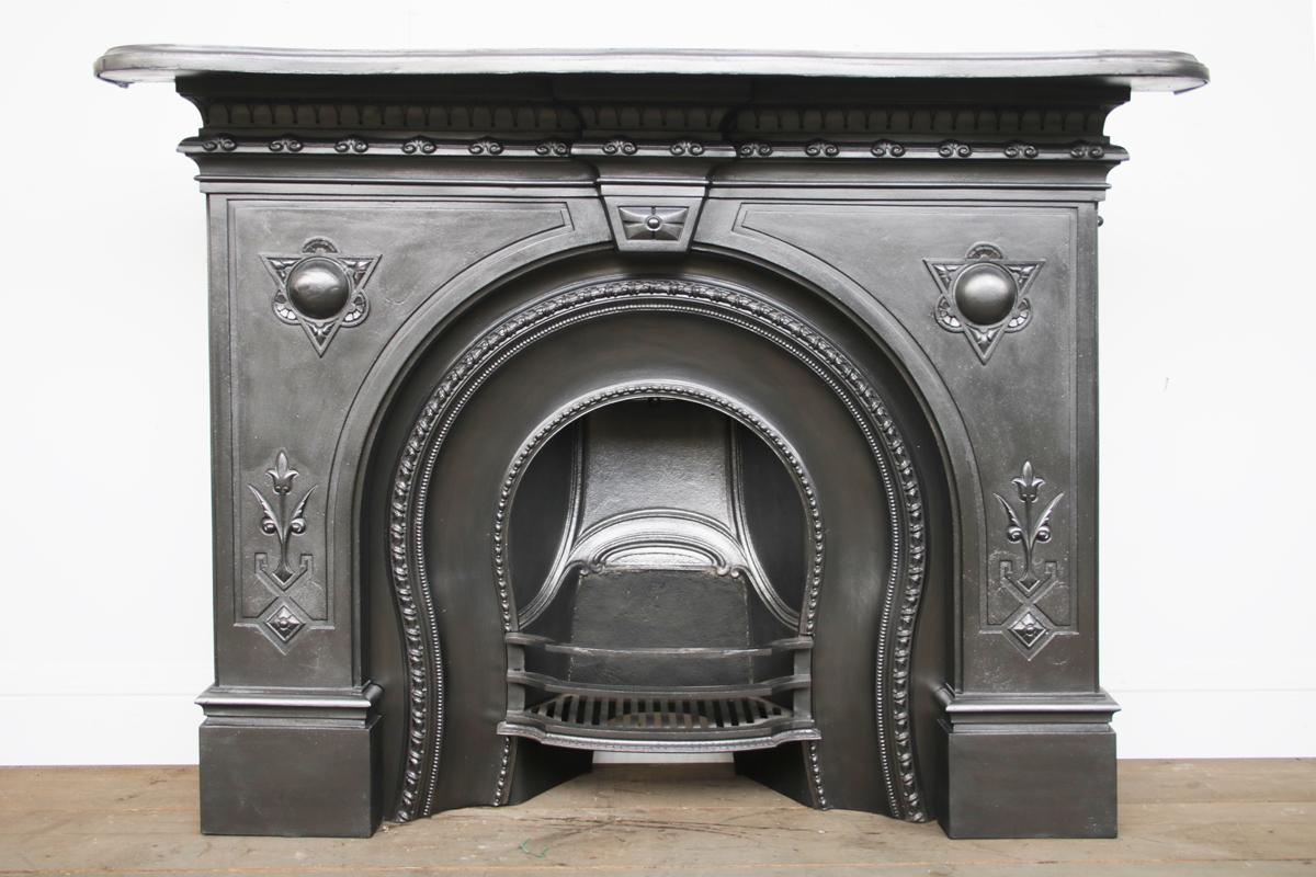 A restored 19th century mid Victorian cast iron arched fire surround with pronounced bosses to the spandrels and decoration below the serpentine shelf. English. Circa 1860.

Finished in traditional black grate polish and pictured with an original