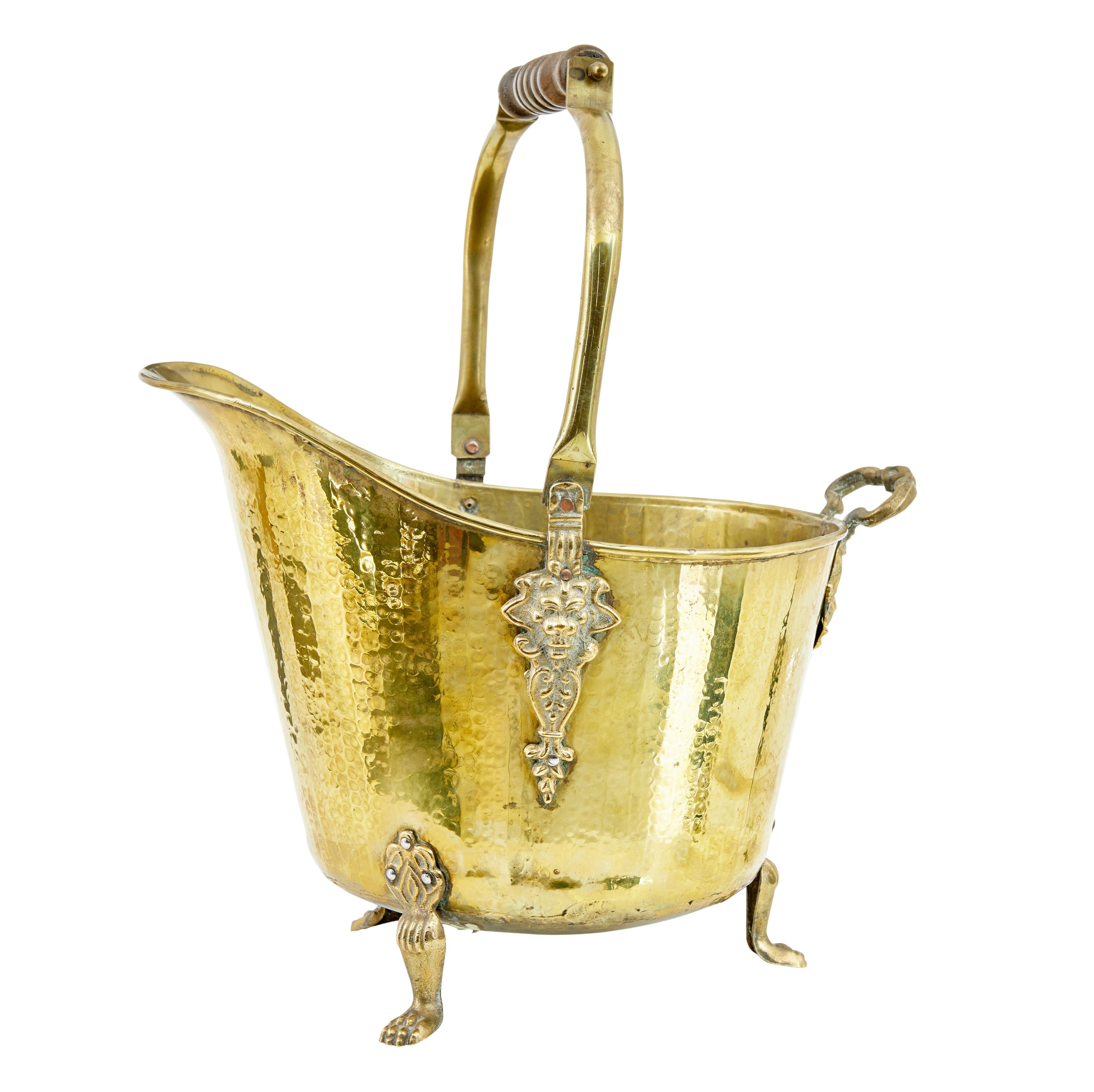 19th century Victorian brass coal scuttle circa 1890.

Decorative cast lion brass masks form the supports for the wood and brass handle.
Standing on 3 paw feet, good quality example from the 19th century.

Minor expected surface marks.  Handle with