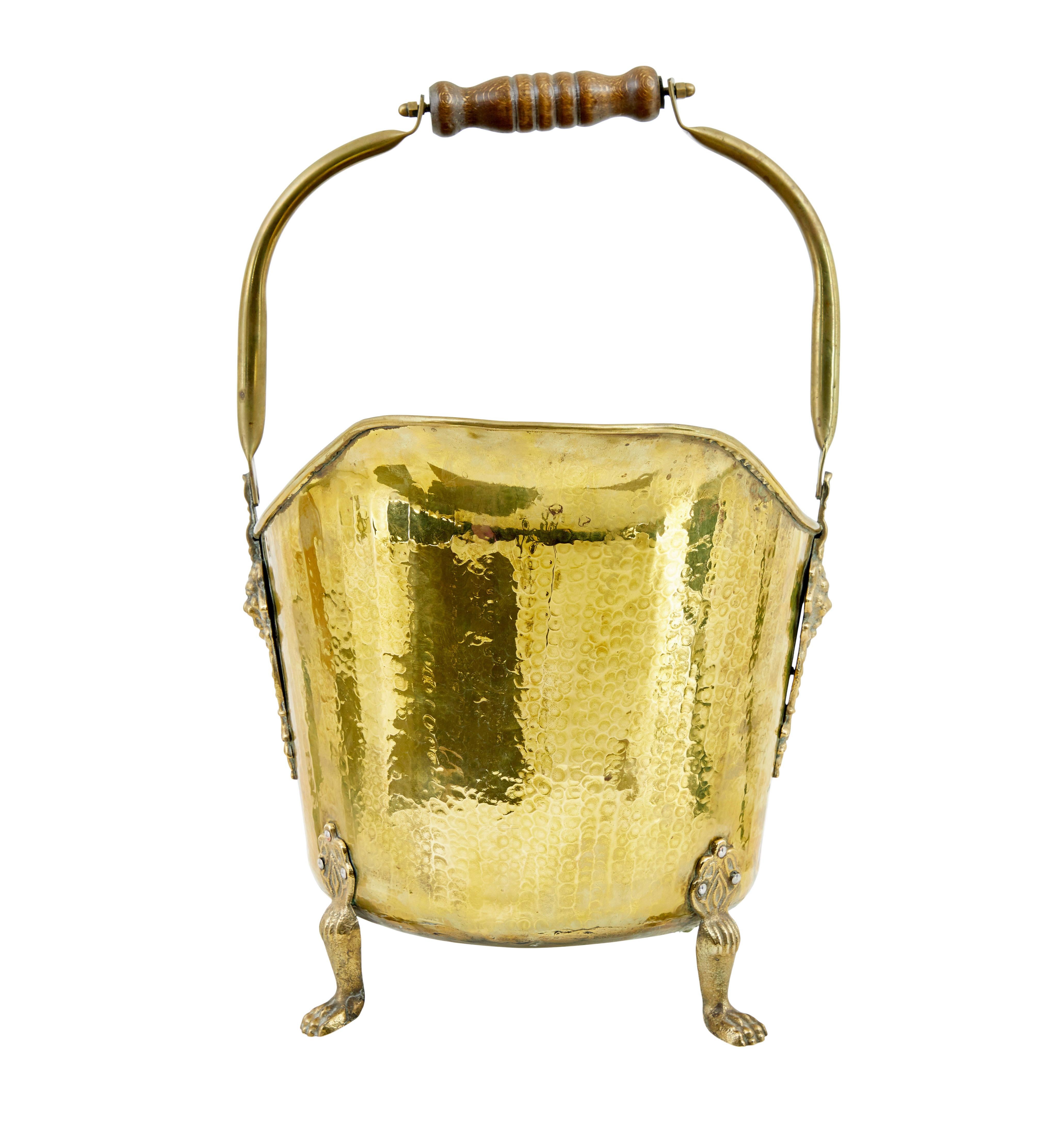 19th century victorian brass coal scuttle circa 1890.

Decorative cast lion brass masks form the supports for the wood and brass handle.
Standing on 3 paw feet, good quality example from the 19th century.

Minor expected surface marks.  Handle with