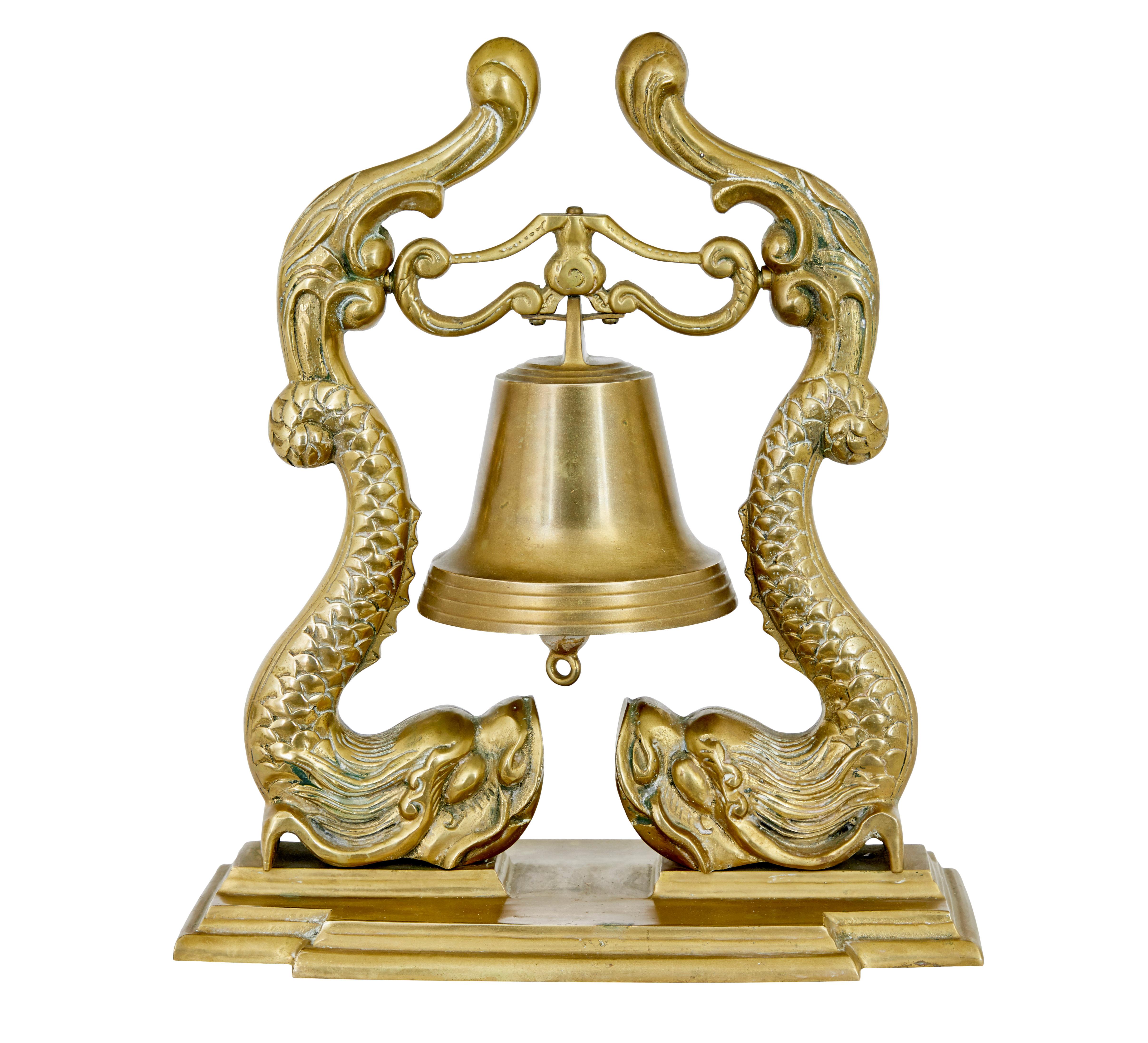 19th century Victorian brass decorative dinner bell circa 1890.

Features 2 stylised fish which form the suspension arms to support the bell. Standing on plinth base. Would have had a rope from the bottom of the bell, now lacking, but can be easily