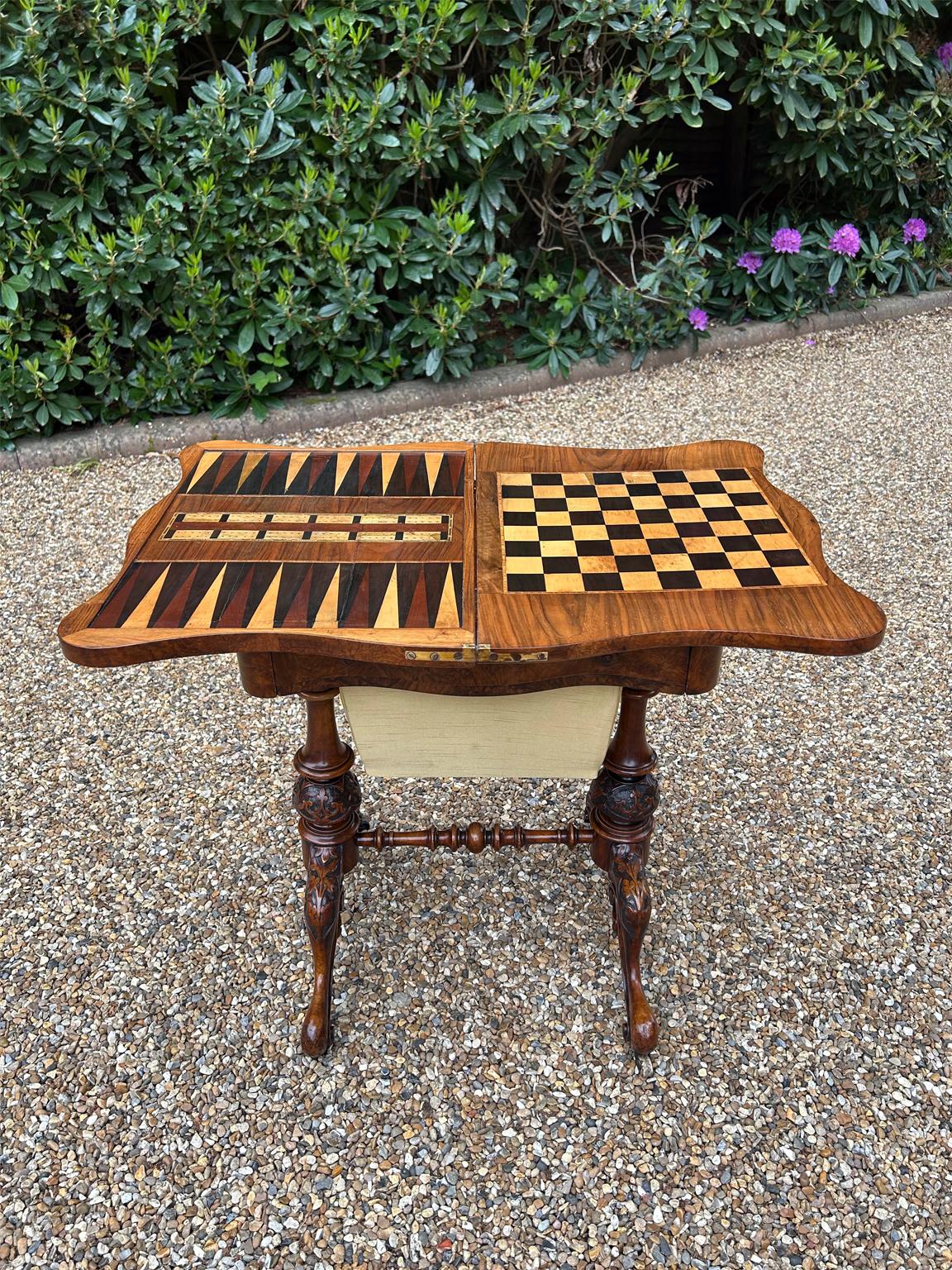 Tavolo da gioco vittoriano in radica di noce del XIX secolo. Aprendo il piano di gioco si scopre una scacchiera e una tavola da gioco in legno di tulipano e bosso, mentre sull'altro lato si trova una tavola da Backgammon e Cribbage in legno di
