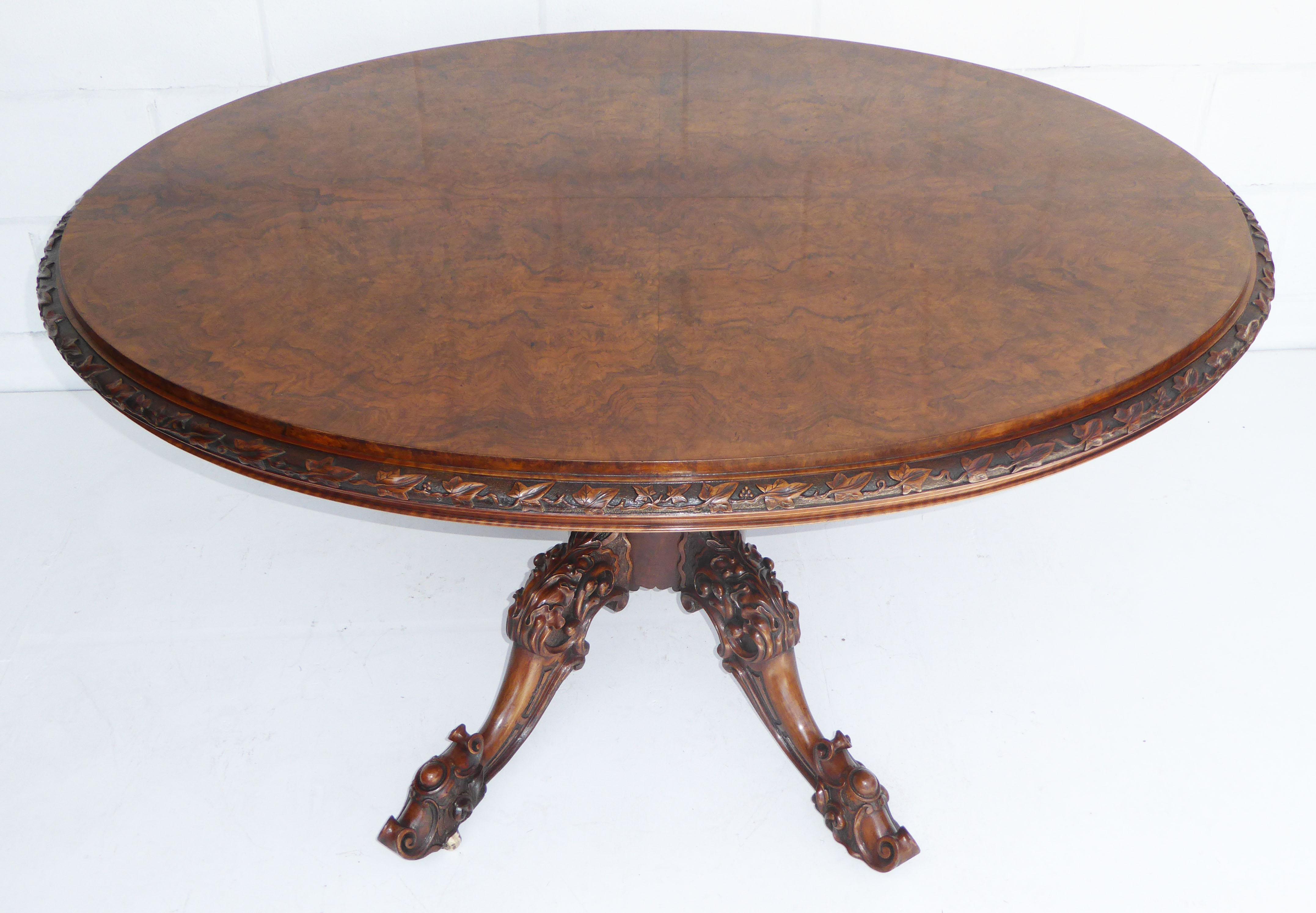 For sale is a fine quality Victorian burr walnut oval breakfast table. The edge of the table is ornately carved with ivy leaves, above an incredibly ornate turned and carved base, terminating on original castors. The table is in very good condition