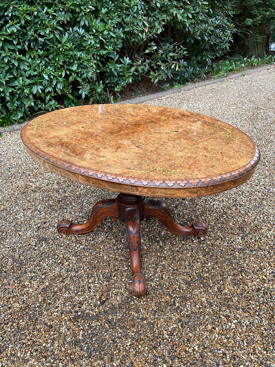 19th century Victorian burr walnut oval tilt-top dining table with floral carved edging and inlaid decoration, raised on a turned and carved baluster column and four carved cabriole legs.

circa: 1850

Dimensions:
Height: 28.5 inches – 72