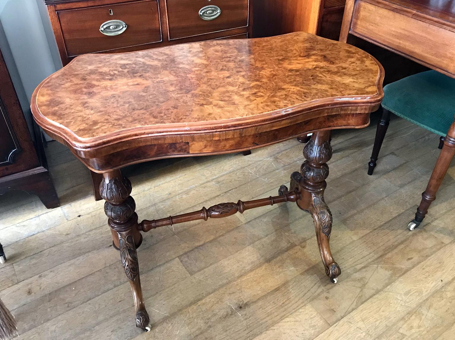 19th century Victorian burr walnut serpentine card table with quarter veneer highly figured burr walnut top and frieze, serpentine in shape with a round end and an inverted corner.

The turned supports are in solid walnut with finely carved