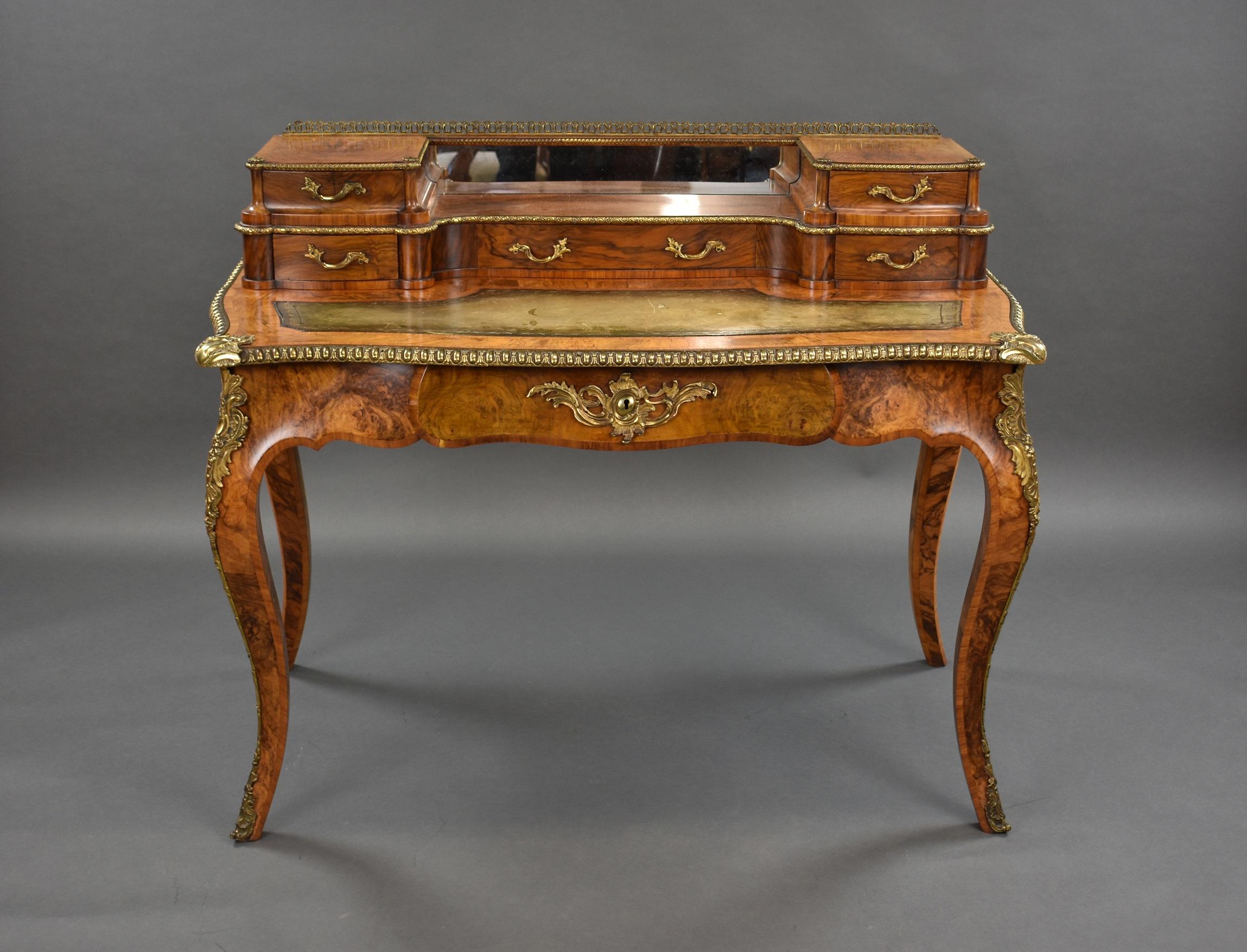 For sale is a fine quality Victorian burr walnut writing table, with gilt brass mounts, the raised back with a pierced gallery above a mirror and fitted with five drawers, above a hand coloured leather hide writing surface over a frieze drawer