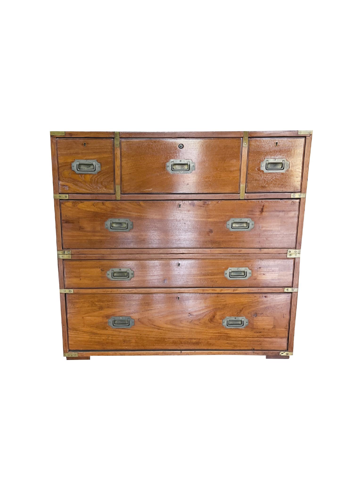 Cómoda de campaña victoriana bien envejecida y cálida, formada por dos piezas de caoba con monturas y tiradores de latón. El cajón superior central se despliega en un escritorio equipado con una superficie para escribir forrada de cuero negro y