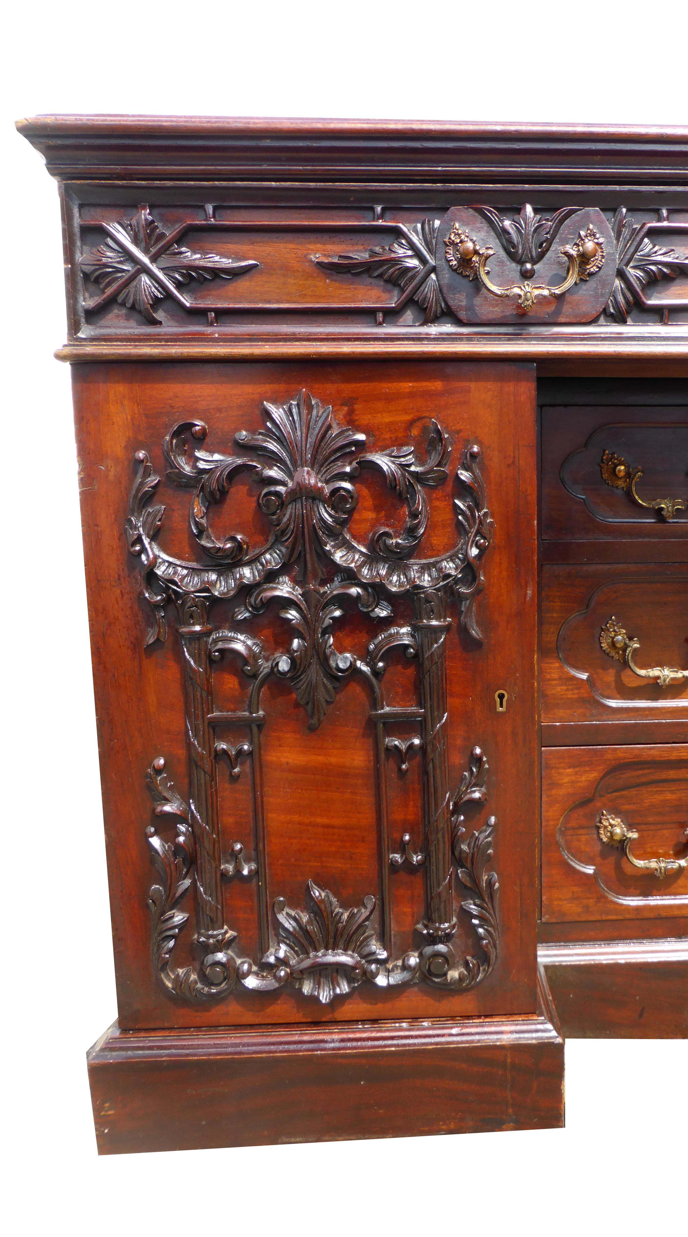 Selling is a top quality, unusual mid-Victorian copy of a Chippendale carved desk. The top drawer of the desk, when opened, reveals a rising writing panel and two lift up panels with storage beneath. All of these panels have a green leather insert