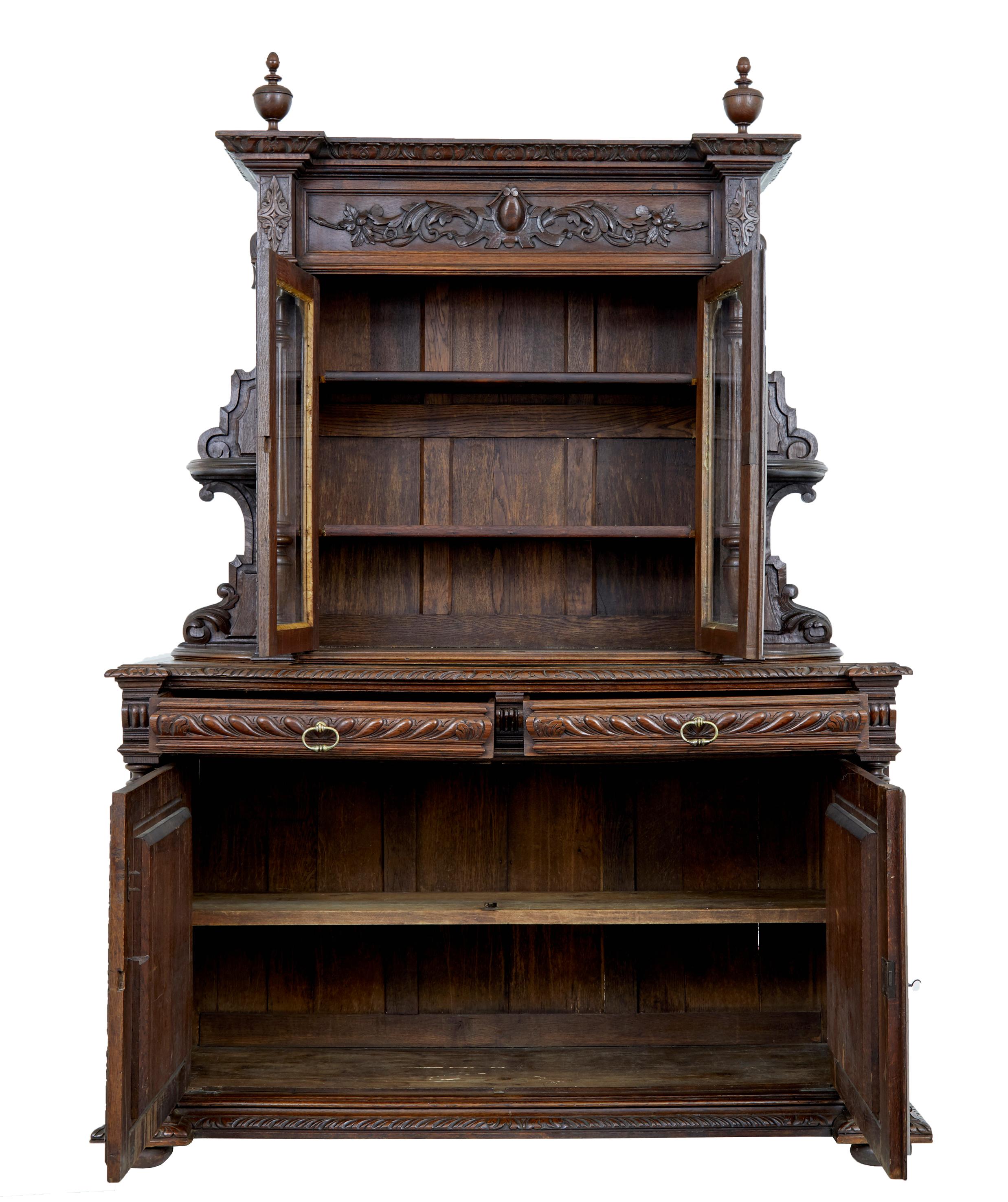 2 part oak dresser circa 1880.

Top section with heavily carved cornice with central cartouche and turned finials. Glazed double doors open to reveal 2 shelves, flanked either side by turned columns and open shelves for display purposes.

Bottom
