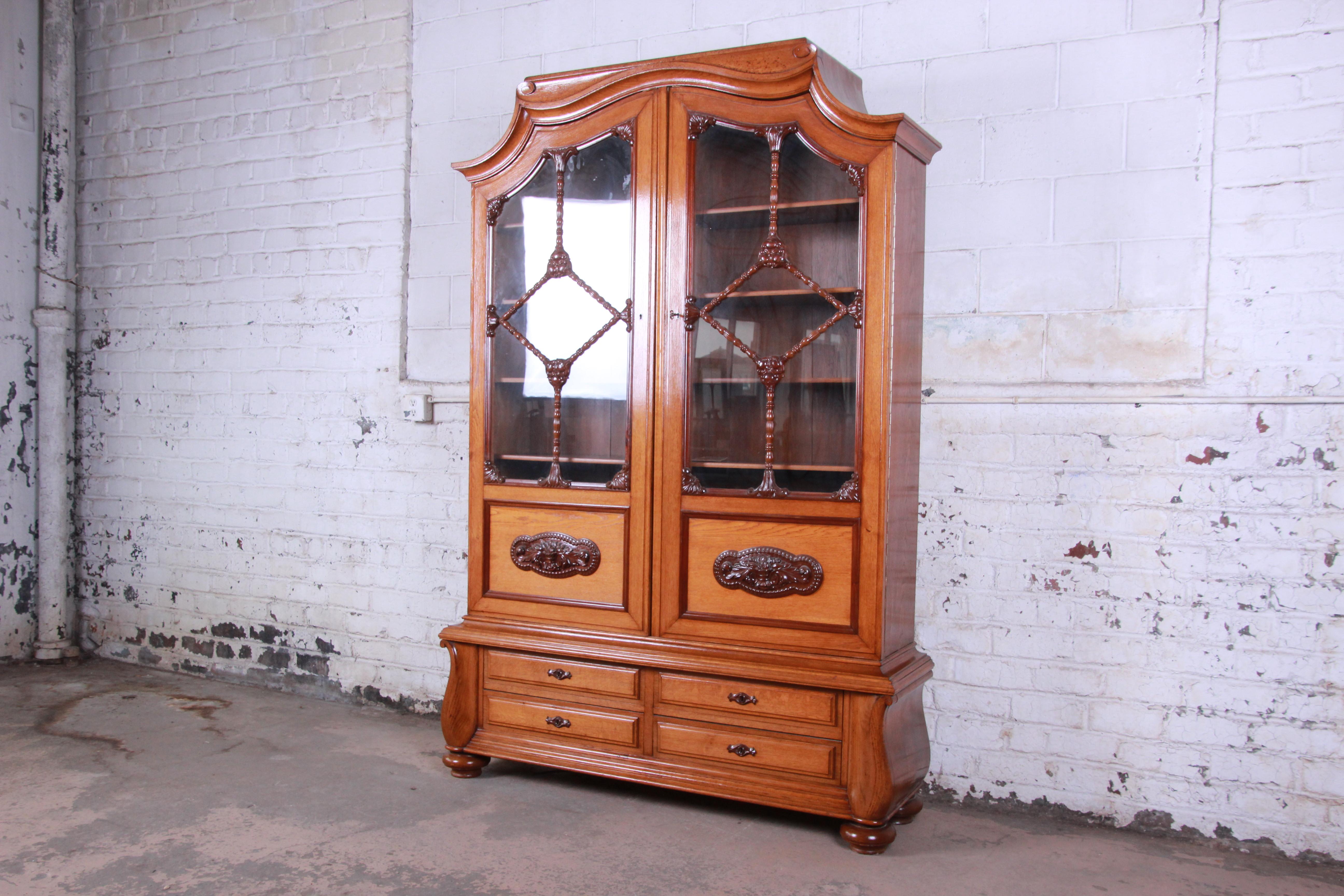 A beautiful 19th century Victorian carved oak bookcase. The bookcase features solid oak construction with gorgeous wood grain and unique carved details. It offers ample storage with four dovetailed drawers and two glass front bookcases with five