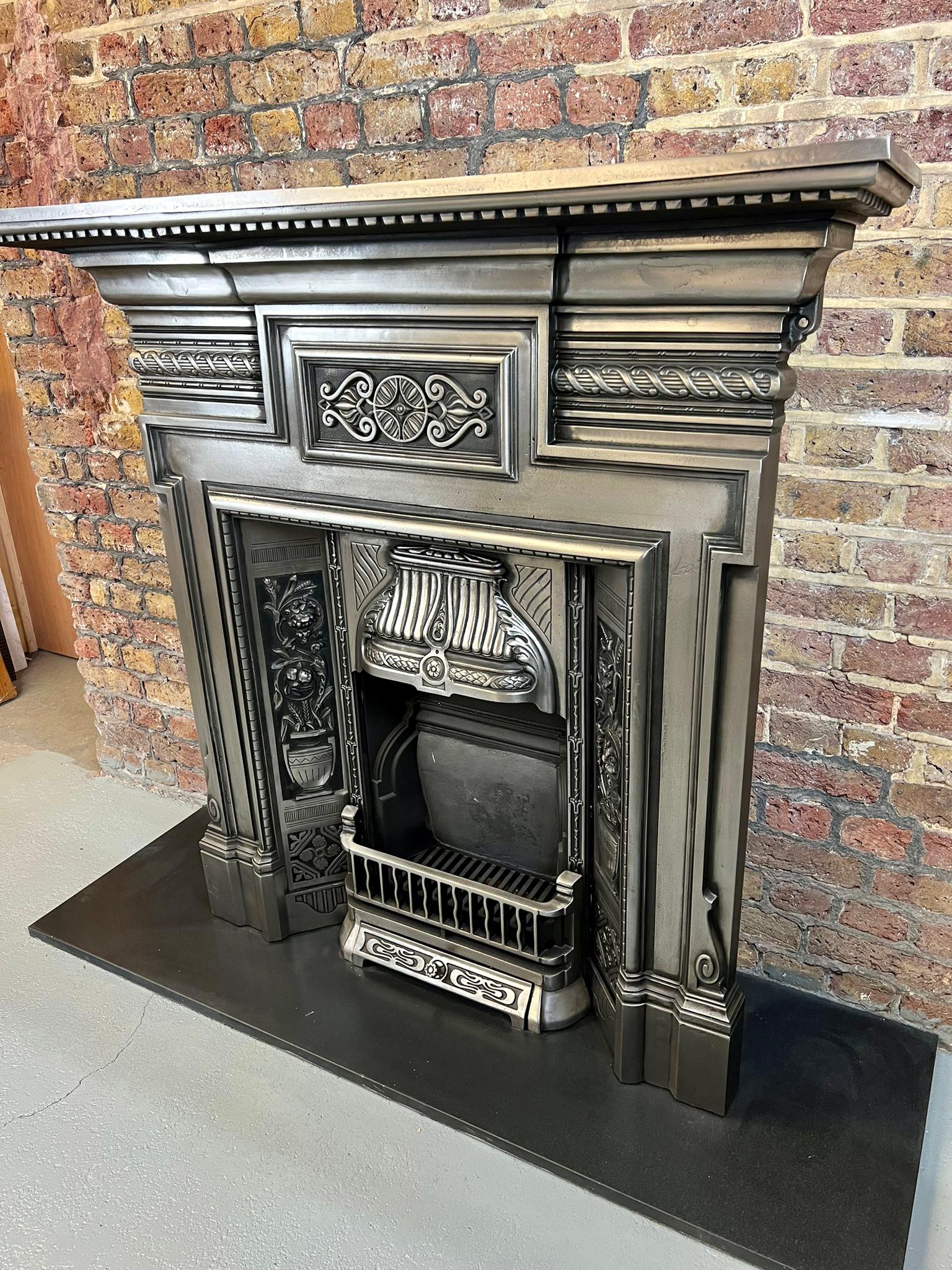 19th century Victorian cast iron burnished combination fireplace.
Original antique fireplace in a polished (burnished) finish with set of floral side panels, cast iron back, bars and canopy hood. Recently salvaged & restored from a London town