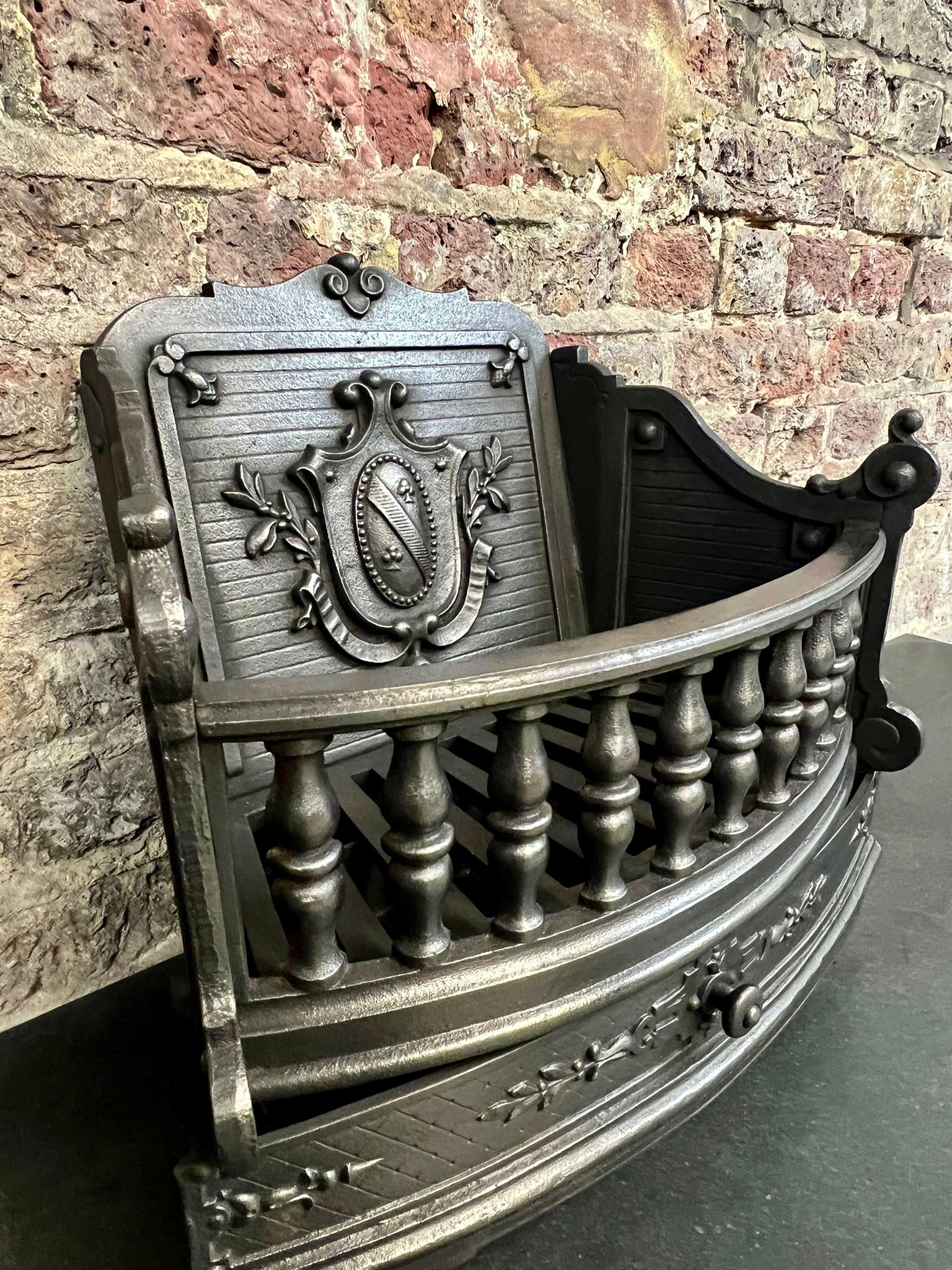 19th Century Victorian cast iron fireplace grate.
A Fine example of an English bow fronted fireplace basket. 
Complete with original shield crested fire back, fire grate, ash pan, ash cover, detailed front bars supported by balusters.
Recently