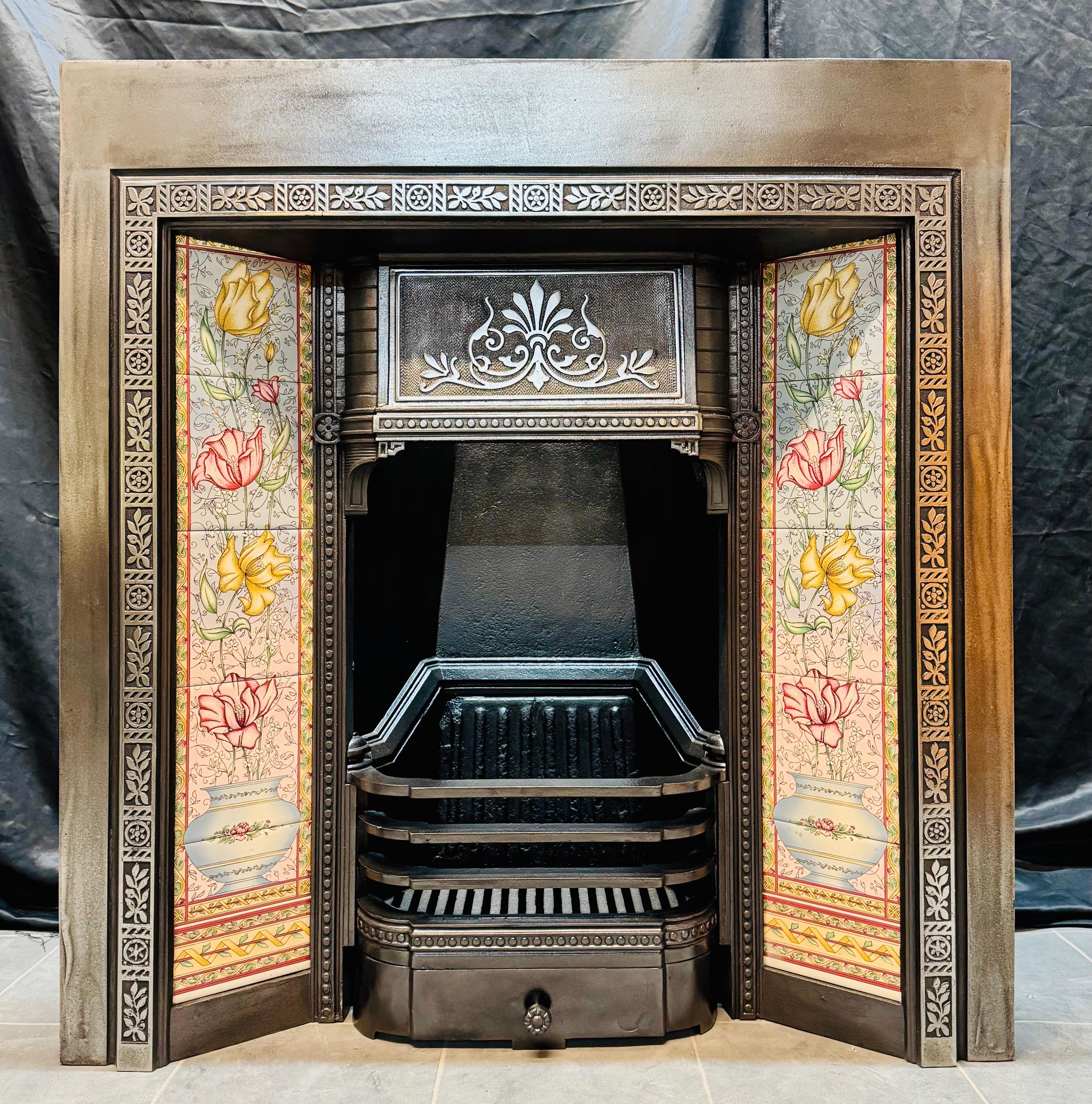 A well balanced and pleasing 19th Century English cast iron fireplace insert with colourful tiles each side. A generous outer frame with a raised cast decorative border, a central chimney hood displaying a well cast high relief detail. 

A three