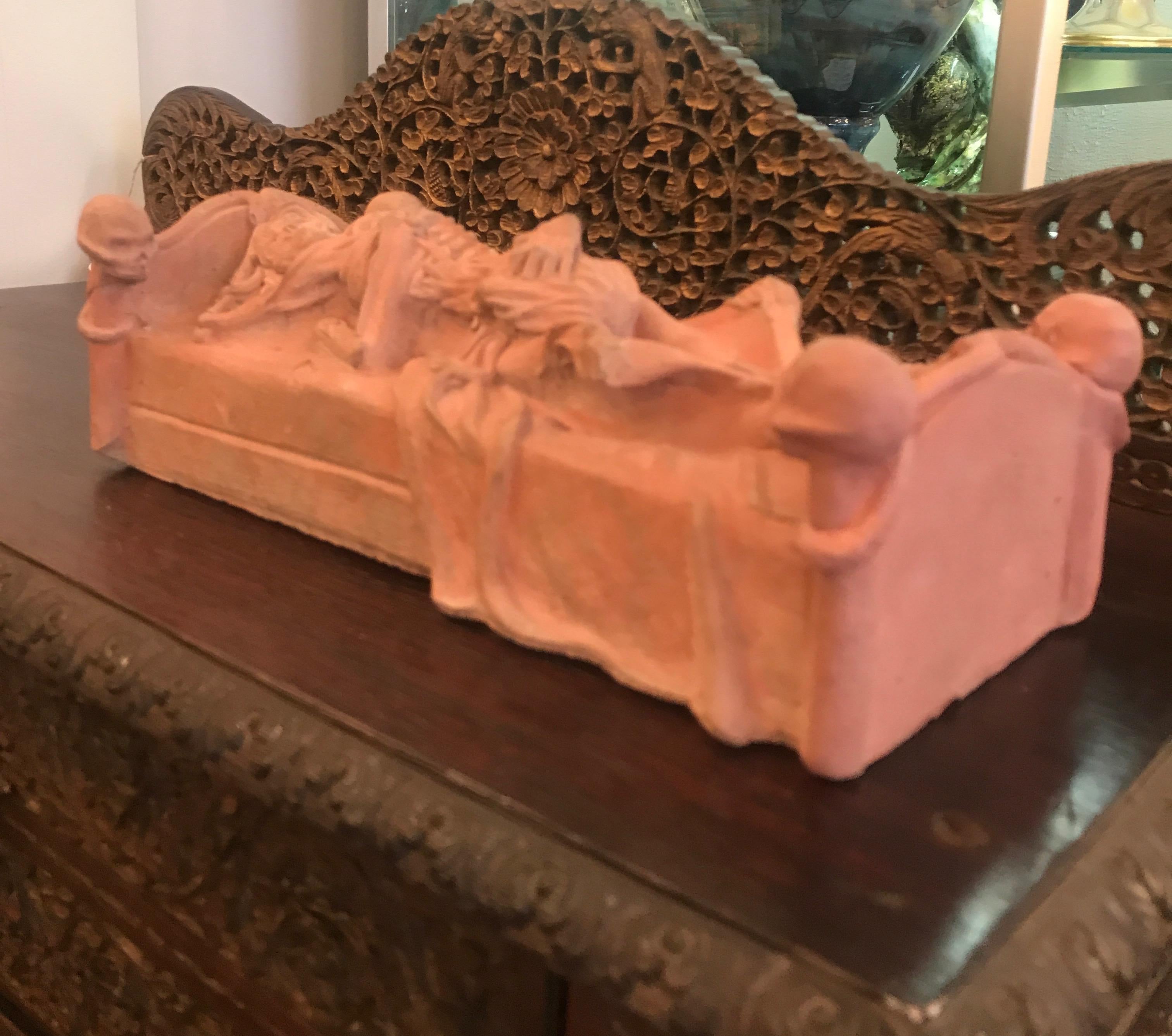 Tabletop sculpture from the 19th century in reddish clay cement of embracing skeletons on a bed with skull bedposts. 11.5 inches long, highly detailed and unusual. The skulls on the top of the bed have broken off and reattached decades ago. .