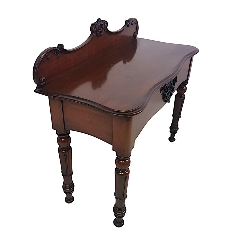 A lovely 19th Century Victorian mahogany console or hall table, the moulded top of serpentine form with shaped and carved gallery back with C Scroll and foliate motif detail raised over frieze with intricately carved flour de lis flanked with C