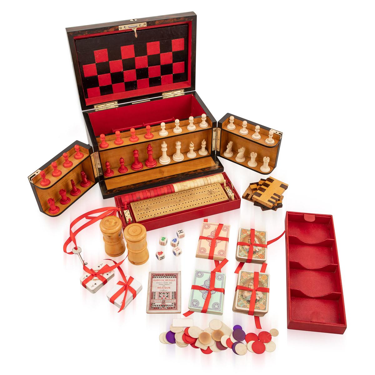 Antique late-19th century Victorian coromandel cased games compendium, the interior comprising a carved white and red chess set, draughts, dominoes, dice, cribbage board with markers, leather bound boards for games, playing cards, droughts counters,