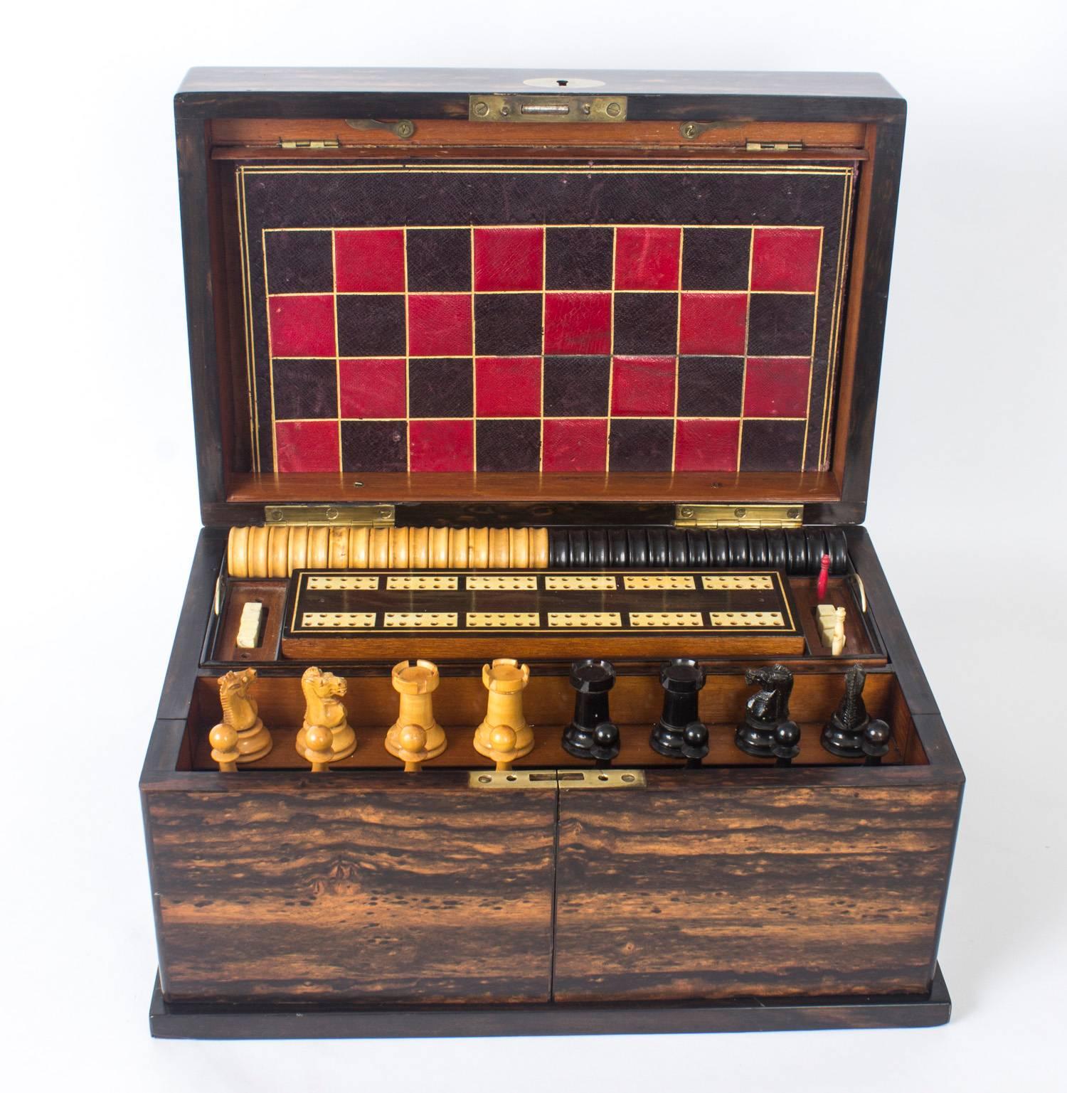 This is a wonderful antique Victorian coromandel games compendium, circa 1860 in date.

The hinged lid reveals fitted compartments, the interior with two lift-out trays fitted with boxwood and ebony draft pieces, a cribbage board, bone dominoes,