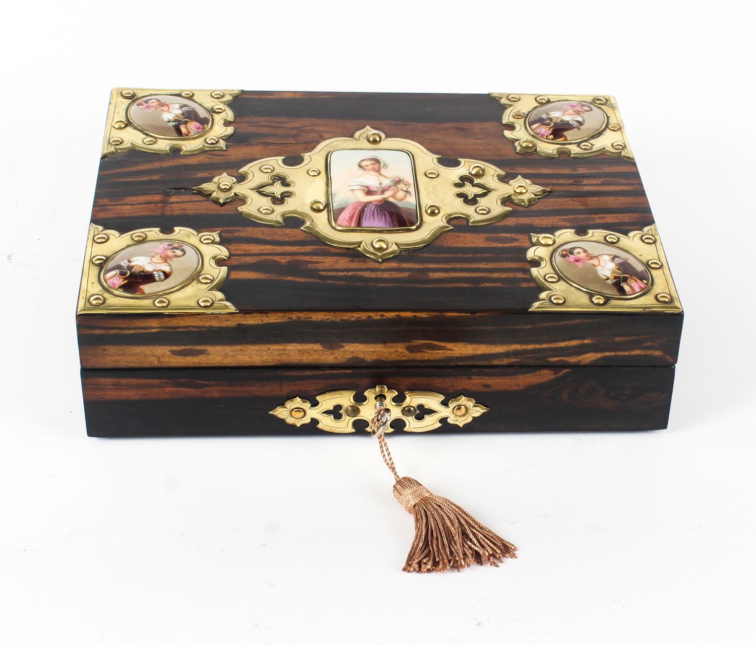 This is a beautiful antique English Victorian Coromandel jewelry casket, circa 1880 in date.

The casket features cut brass neo Gothic mounts and a decorative cut brass escutcheon. The lid bears five decorative KPM porcelain plaques depicting
