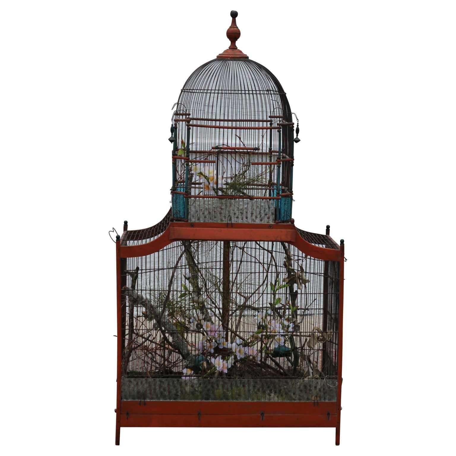 19th century Victorian vintage bird cage with a beautiful top cupola. The metal cage is accented with a wooden frame, wooden spires, and glass panels. Comes with existing foliage decoration.