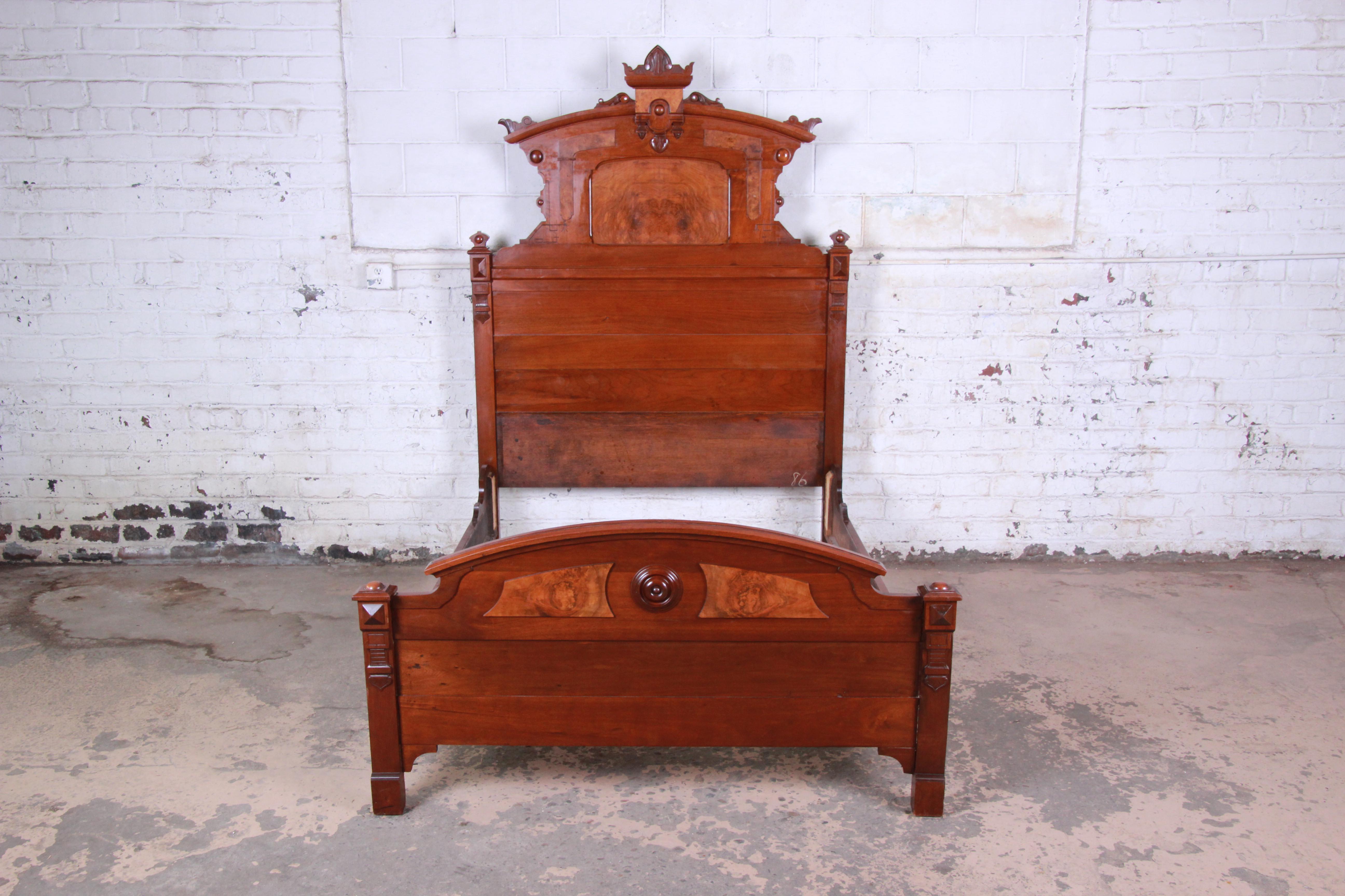 An outstanding 19th century Victorian Eastlake carved walnut and burl wood full size bed. The bed features stunning wood grain and beautiful carved wood details. It is solid, sturdy, and fully functional. An impressive statement piece, with a nearly
