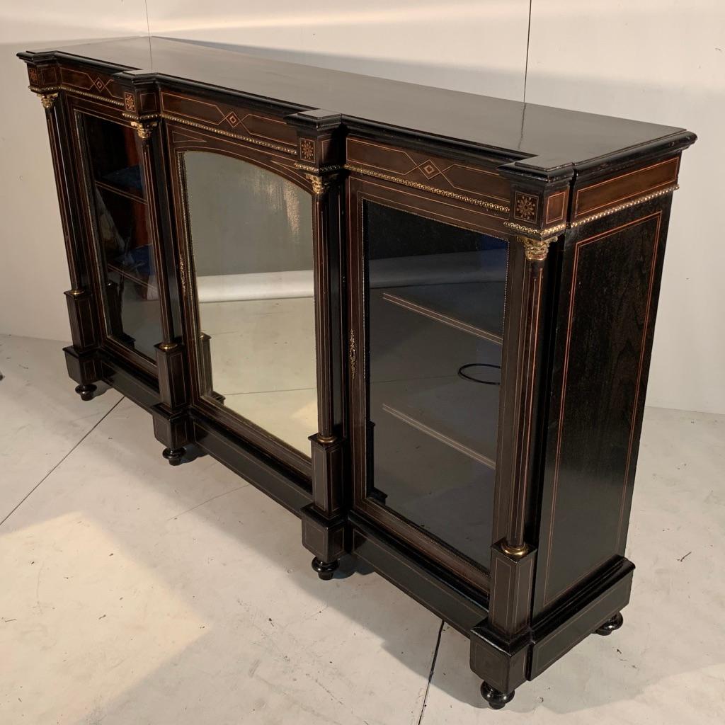 Really stunning Victorian ebonized Credenza sideboard with original brass work, marquetry inlays and with its original two plain glass doors and the central mirrored door is also the original.
Very decorative piece but is also quite refined and