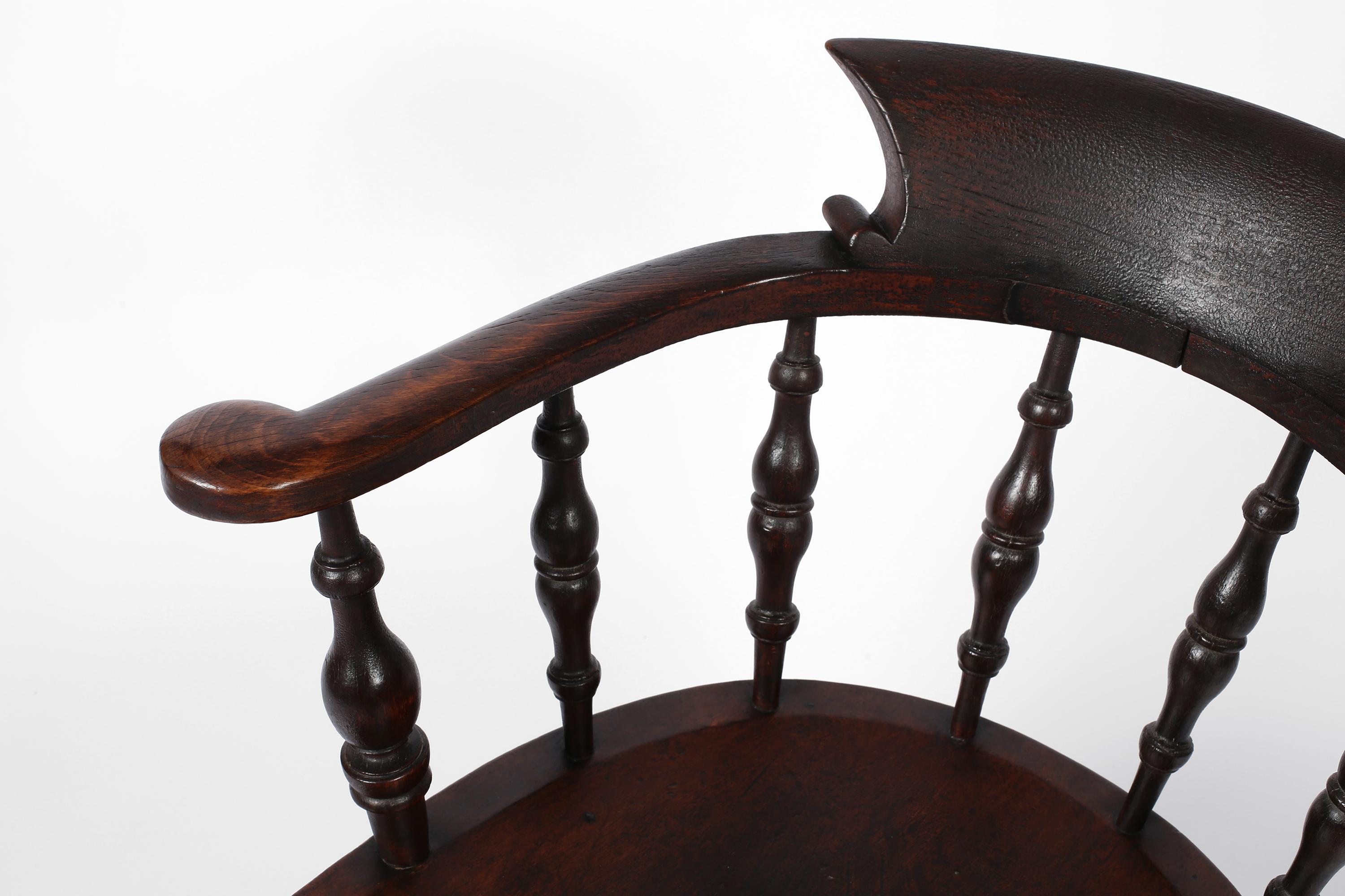 Ein hübsches Beispiel für einen viktorianischen Sessel mit Bogenlehne, der oft als Kapitäns- oder Rauchersessel bezeichnet wird. Geschnitzt und gedrechselt aus Ulme und Eiche, mit einer reichen Patina, die durch die starke Abnutzung der