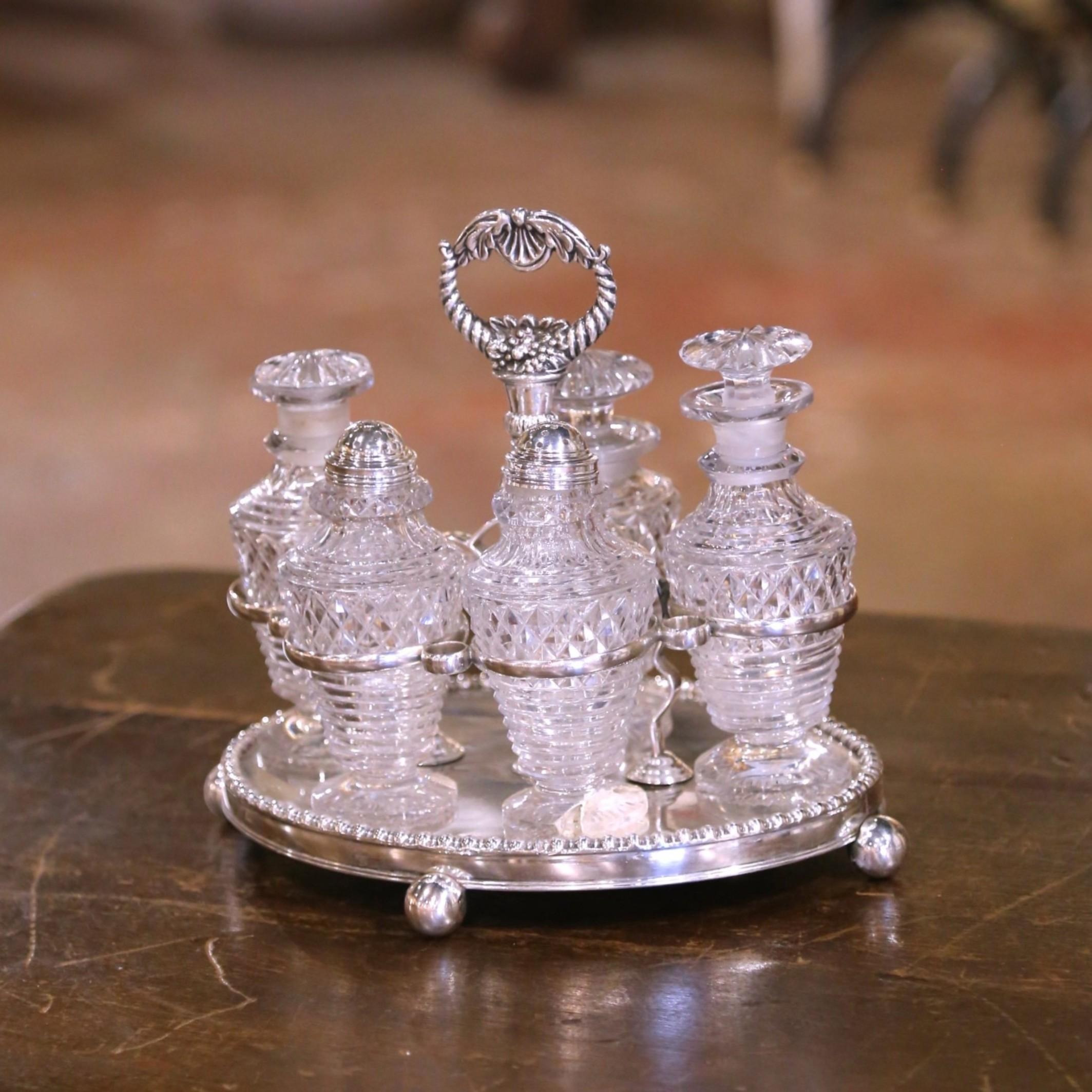 Apportez un charme victorien raffiné à votre table avec cet ensemble de burettes anglaises anciennes. Fabriqué en Angleterre vers 1880, sur un plateau circulaire en métal argenté reposant sur des pieds en forme de boule et orné d'un bord perlé,