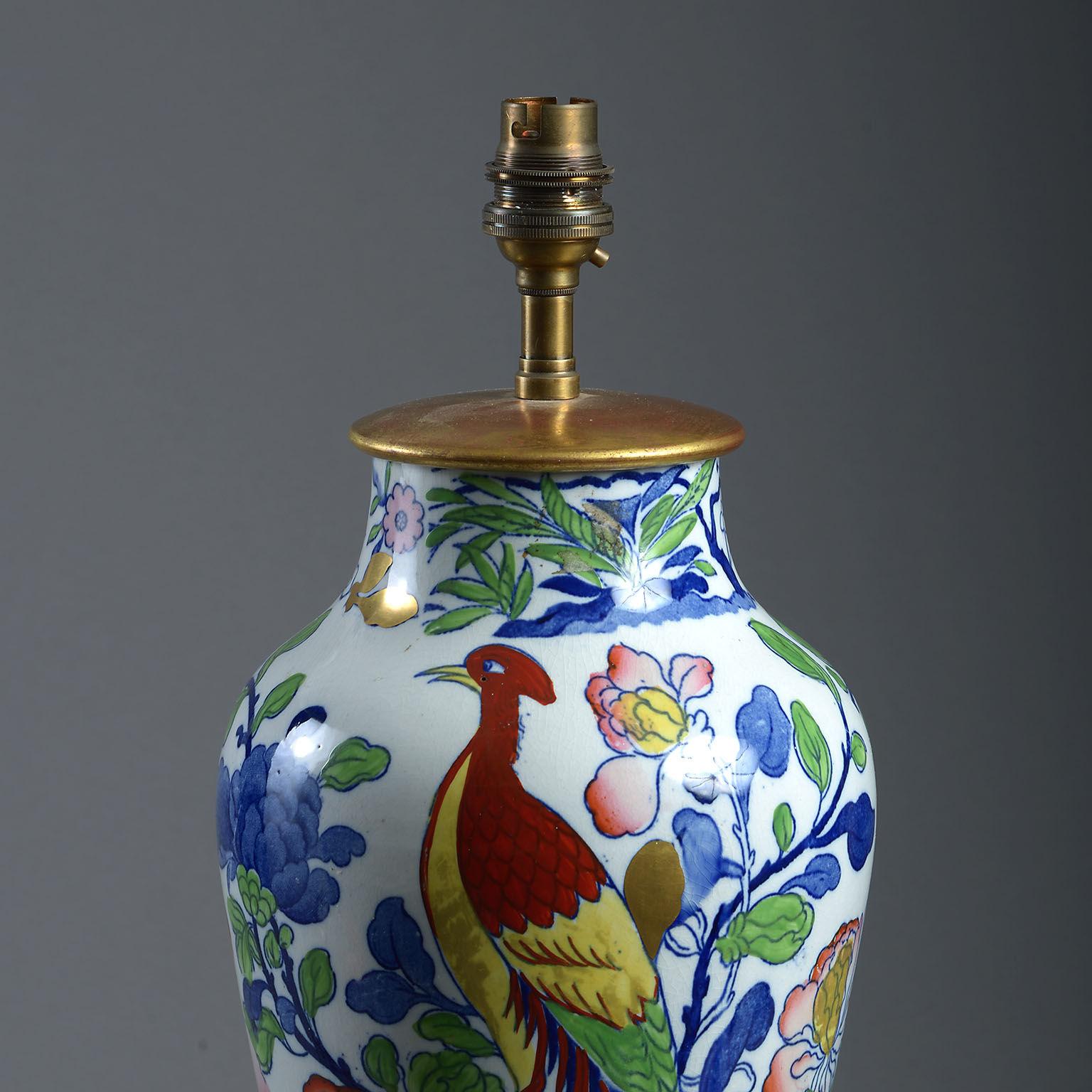 The baluster form decorated with an exotic bird amongst foliage, in colours over a blue transfer. 

With a giltwood cover and standing on a giltwood base. 

Wired with cloth-covered flex.