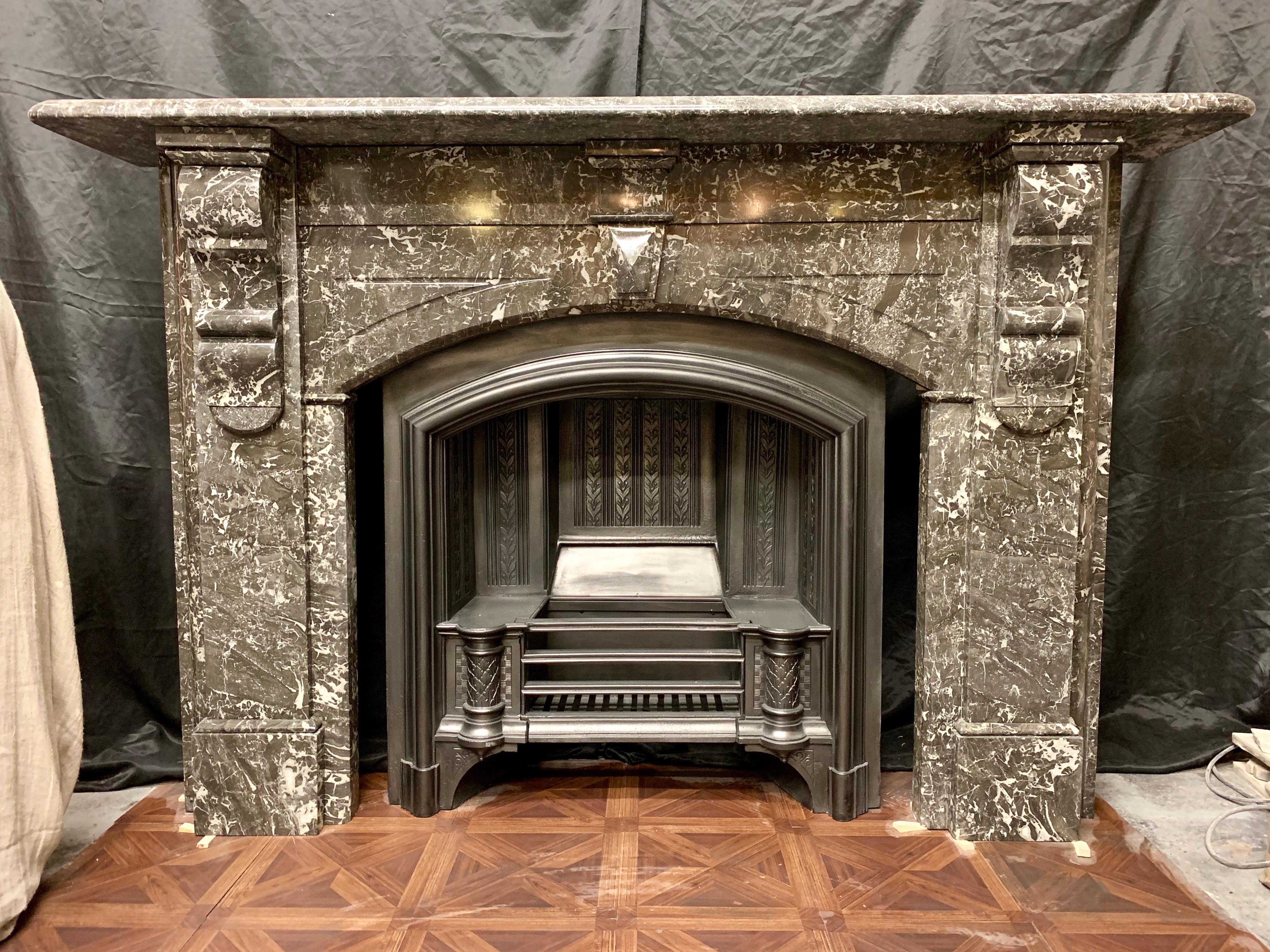 A large and elegant 19th century Victorian slow arched fireplace surround in polished soft dark grey Saint Anne des Pyrenees marble.
The wide moulded shelf rests on large geometric corbeled jambs with block and splayed capping above, the returns