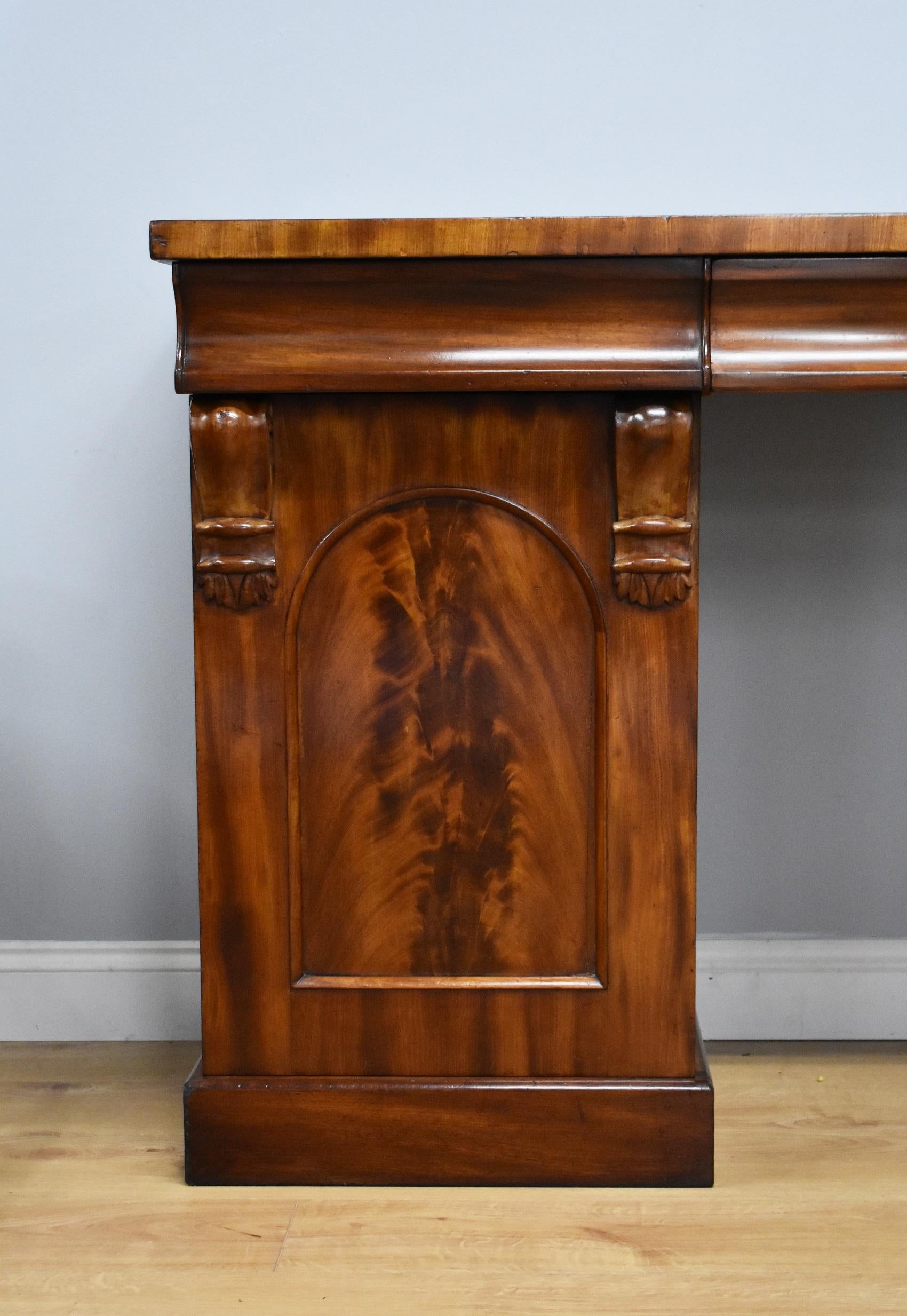 For sale is a good quality Victorian flame mahogany pedestal sideboard. The top has three drawers, one long in the centre, flanked by a short drawer on either side. The top section fits onto two pedestals, each having carved corbels, and arch